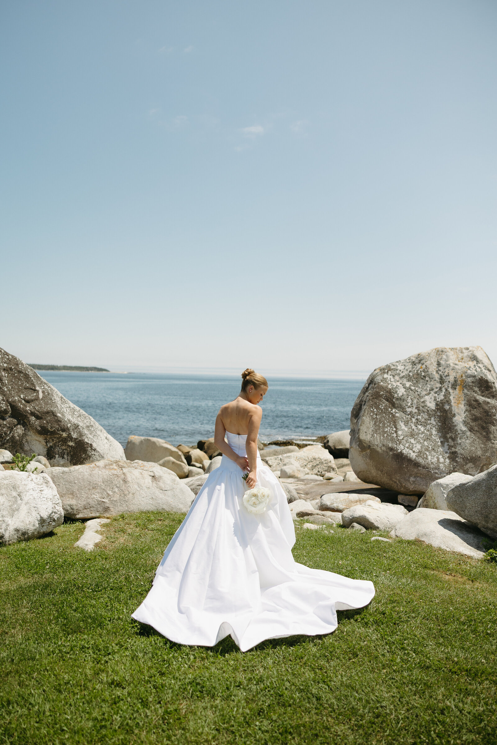 A bride poses for a bridal portrait along the water after getting married at Bullpoint Estate in Nova Scotia. 