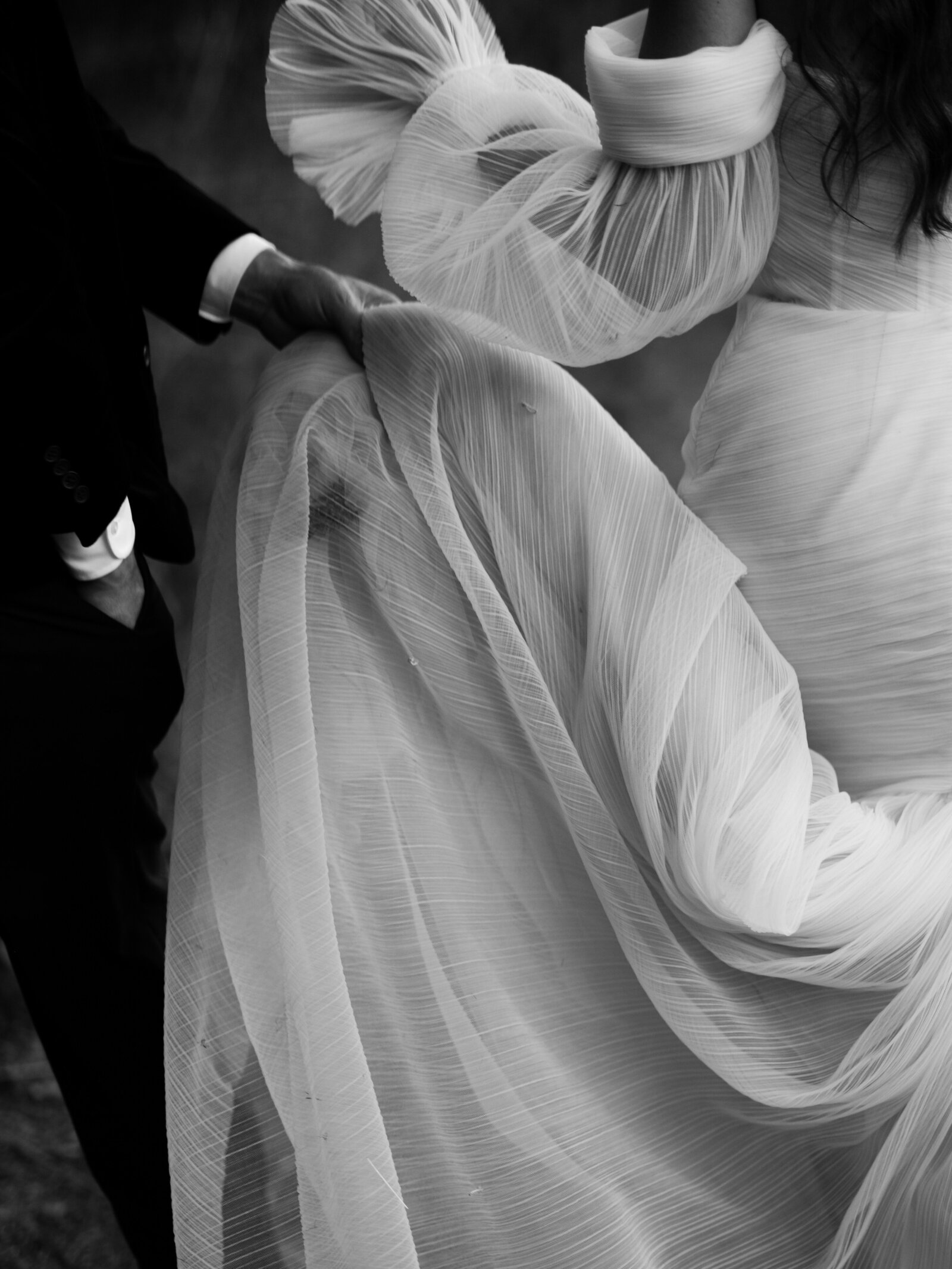 Brides tulle wedding dress fabric being lifted up by groom