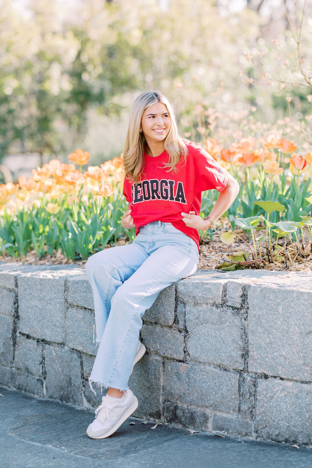 Girl wearing red shirt saying Georgia sits on rock wall