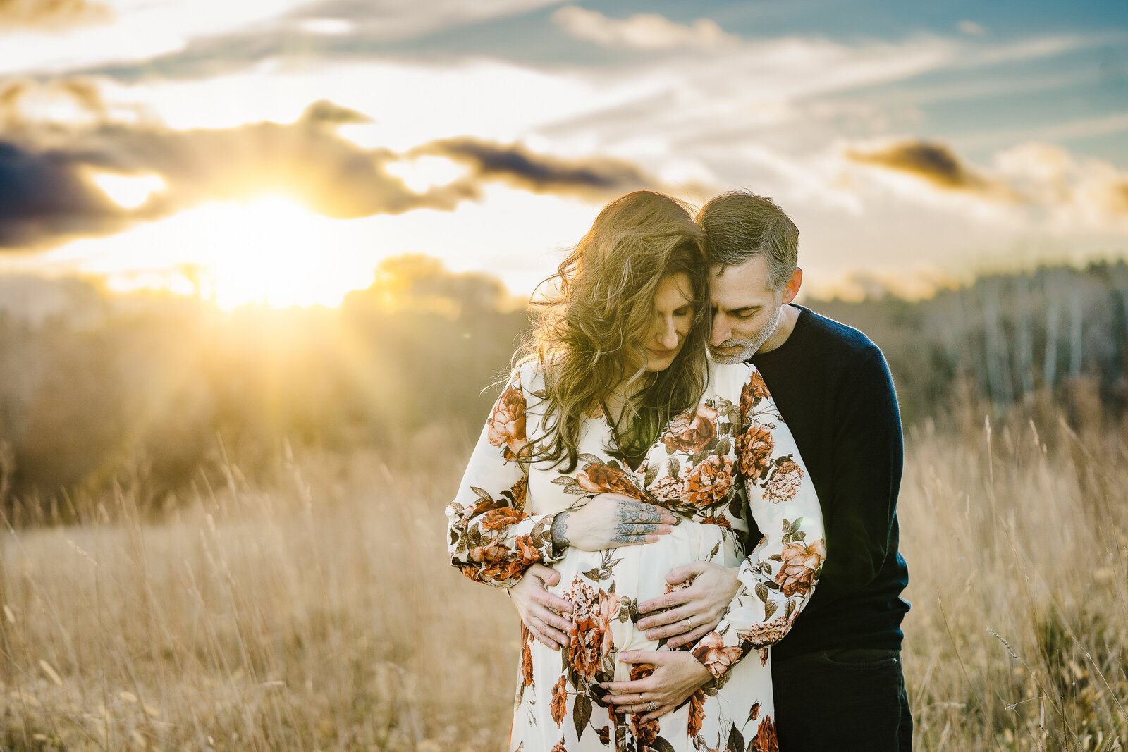sun bursts through clouds during maternity photoshoot in field