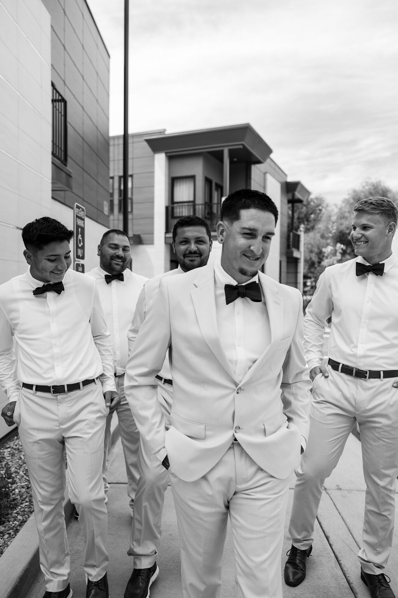 Black and white image of groomsmen laughing and walking in Utah