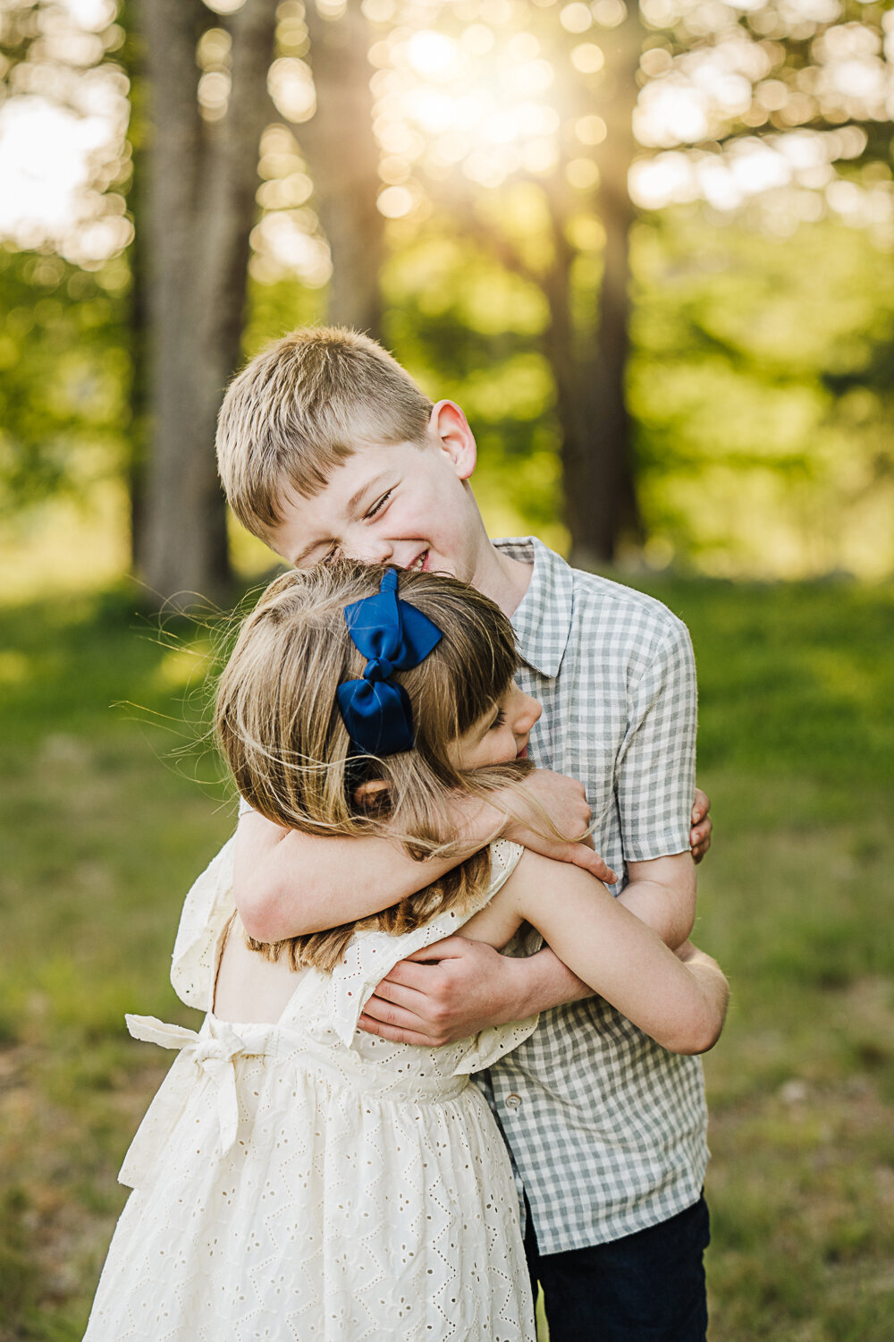 big brother hugs little sister with his eyes closed for family photos