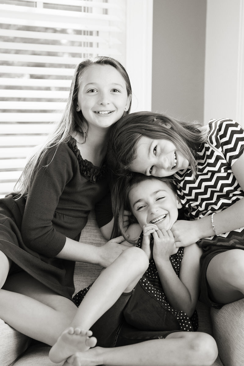 Three siblings smiling and leaning on each other 