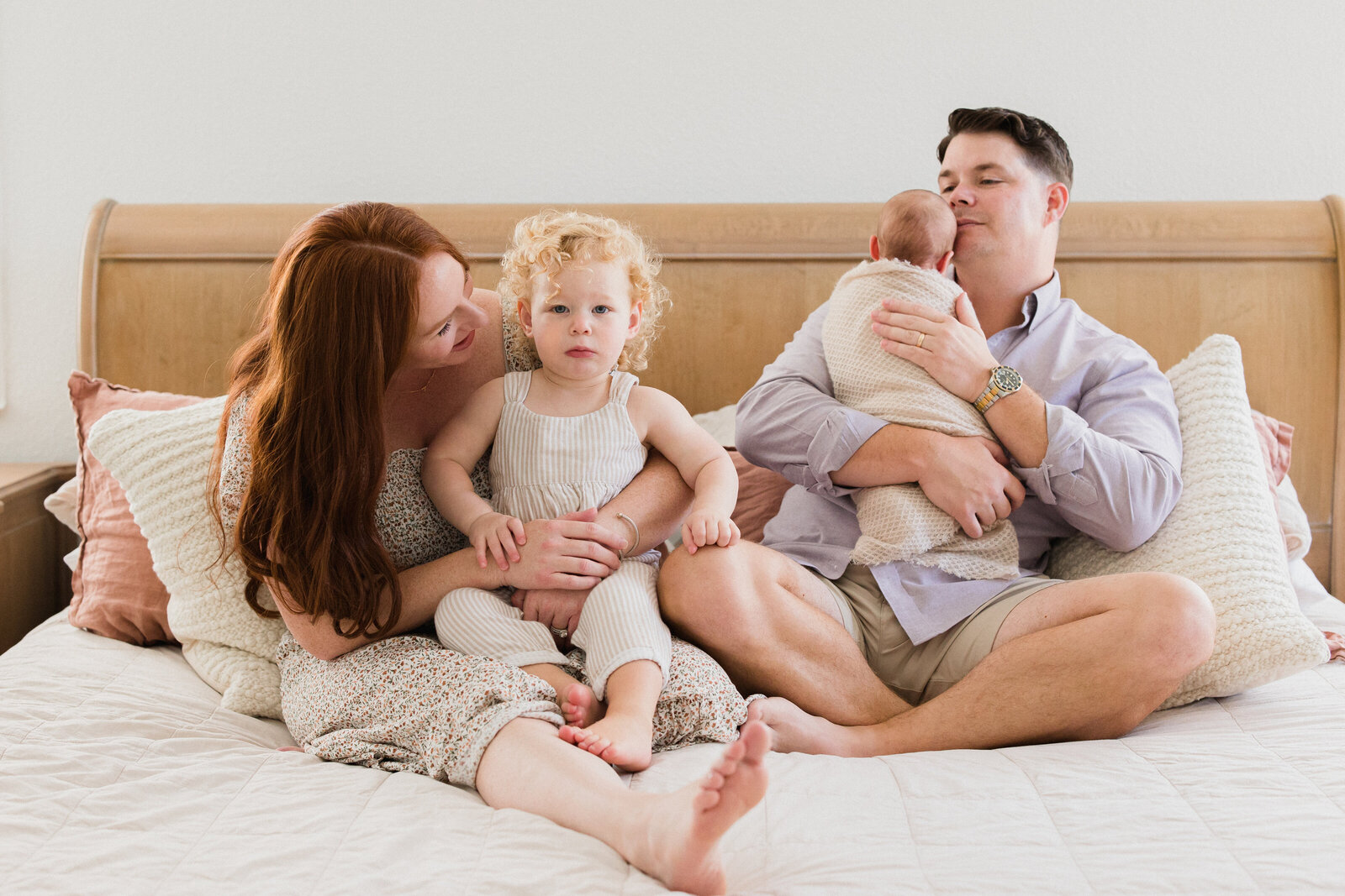 Mom and dad snuggle in bed with their newborn baby and his older sister during their family session in Tampa