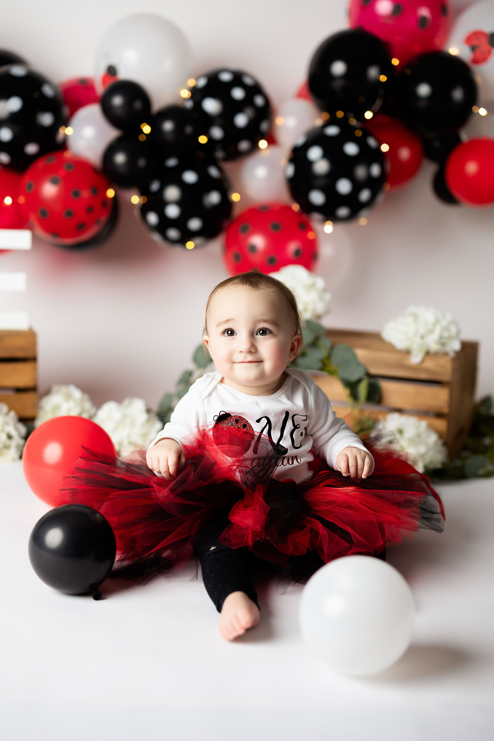 Adorable baby girl in a black and red tutu , smiles up at the camera