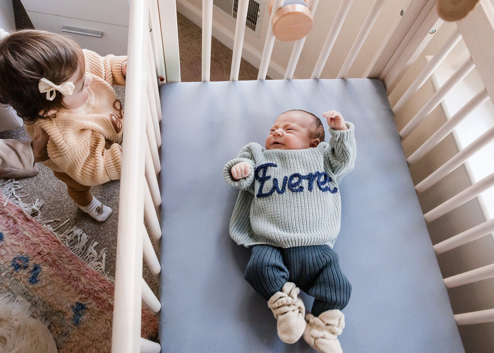 Lifestyle portrait of newborn baby and big sister in the nursery