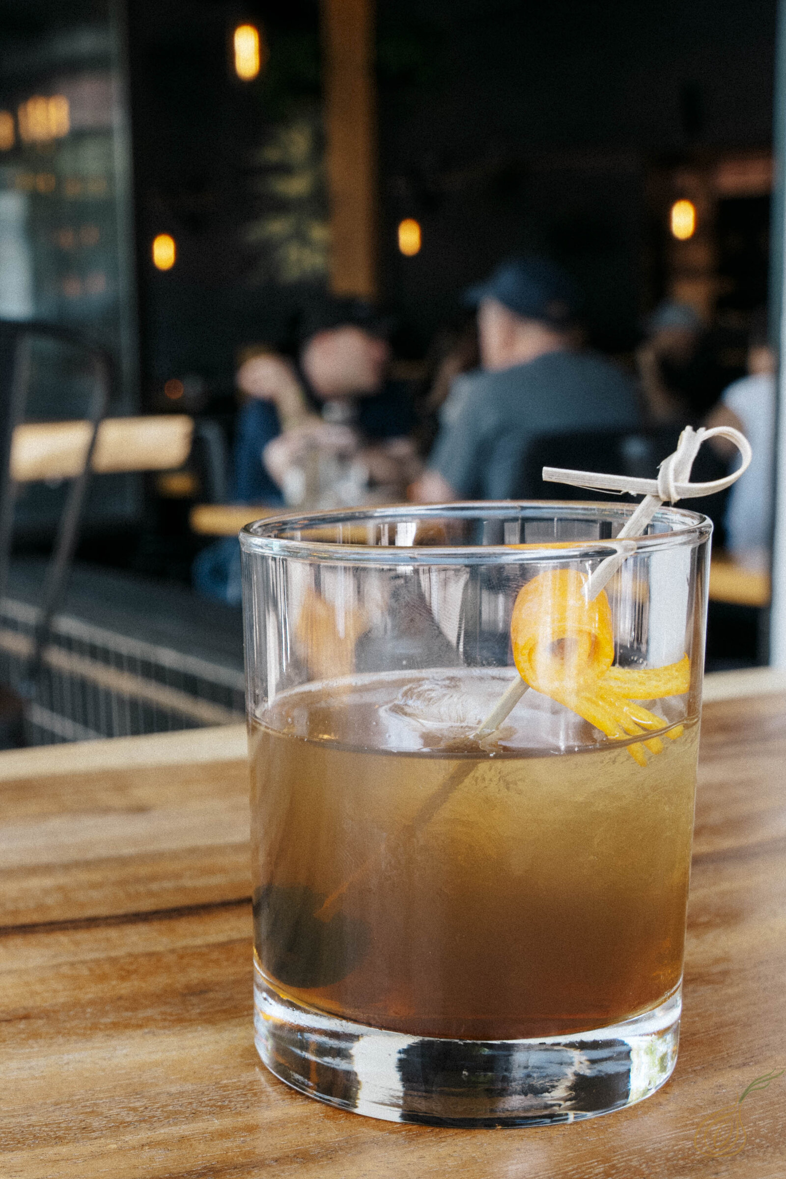 A glass of whiskey rests on a polished wooden table, showcasing its rich amber color and inviting appearance.