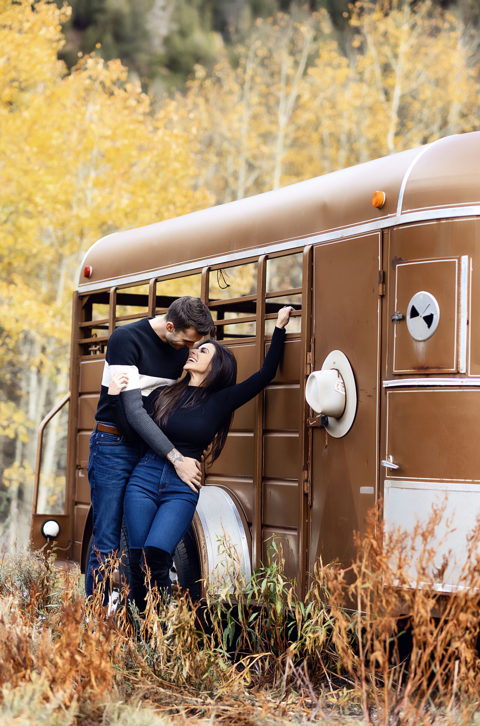 A good looking couple pose next to a horse trailer during their Aspen engagement photoshoot together.