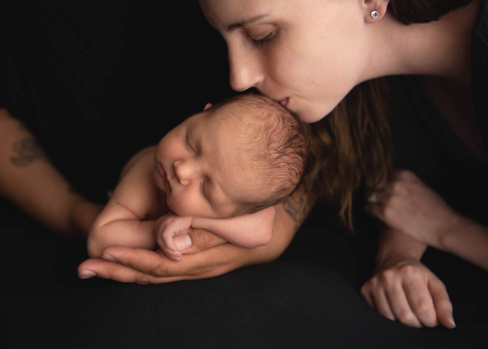 mom kisses newborn during photo session