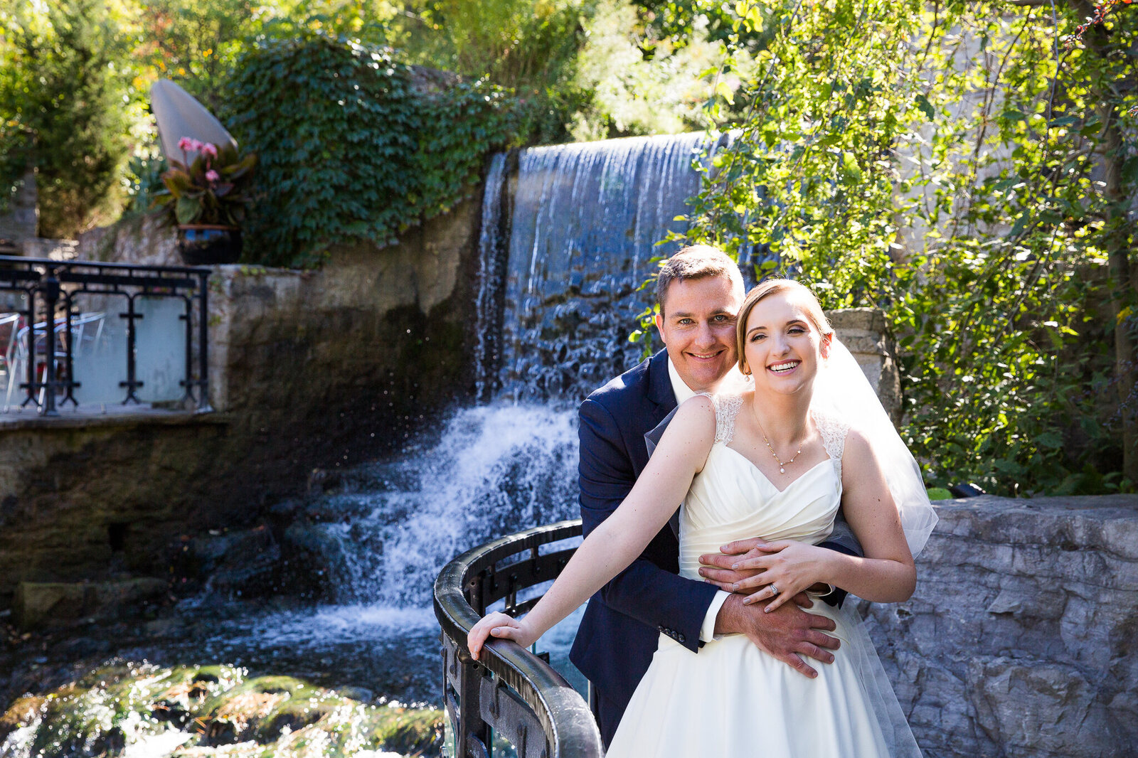 Bride and groom in front of waterfall at Ancaster Mill wedding.