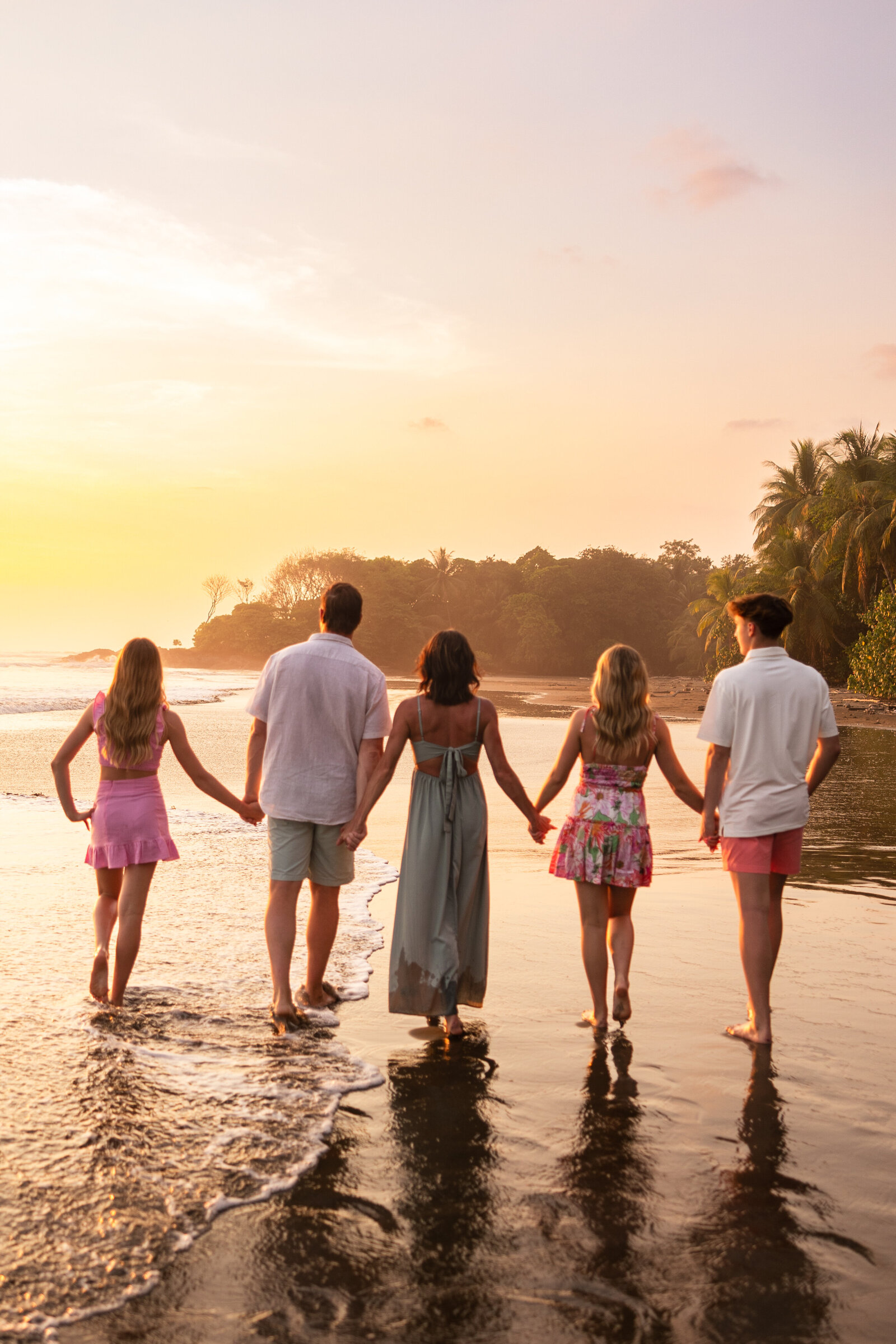 family of 5 with older kids walking on the beach at sunset