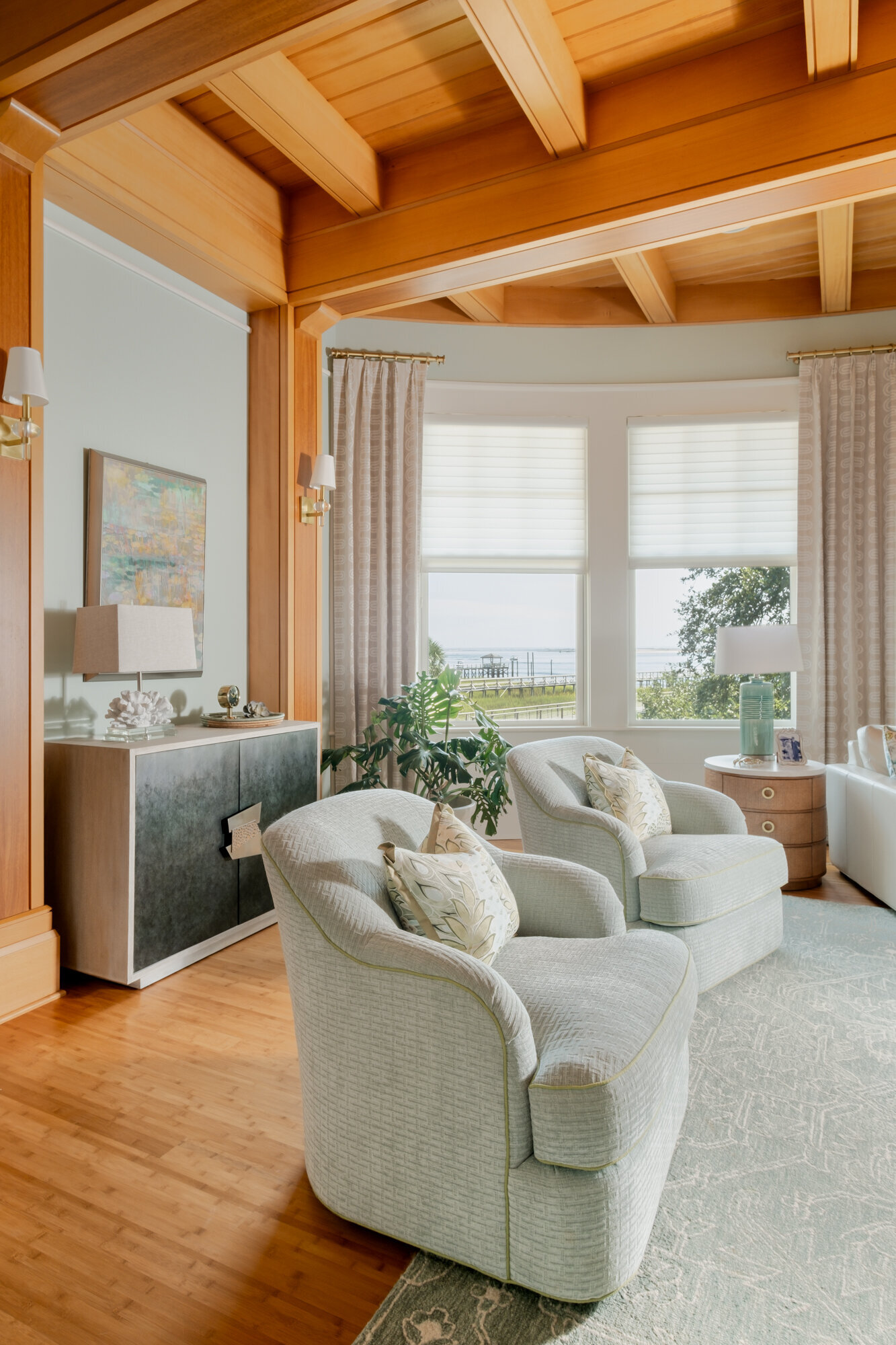 Living room remodel of a coastal home in Wilmington, NC, featuring serene, watery colors, updated flooring, and large windows framing stunning Intracoastal Waterway views."