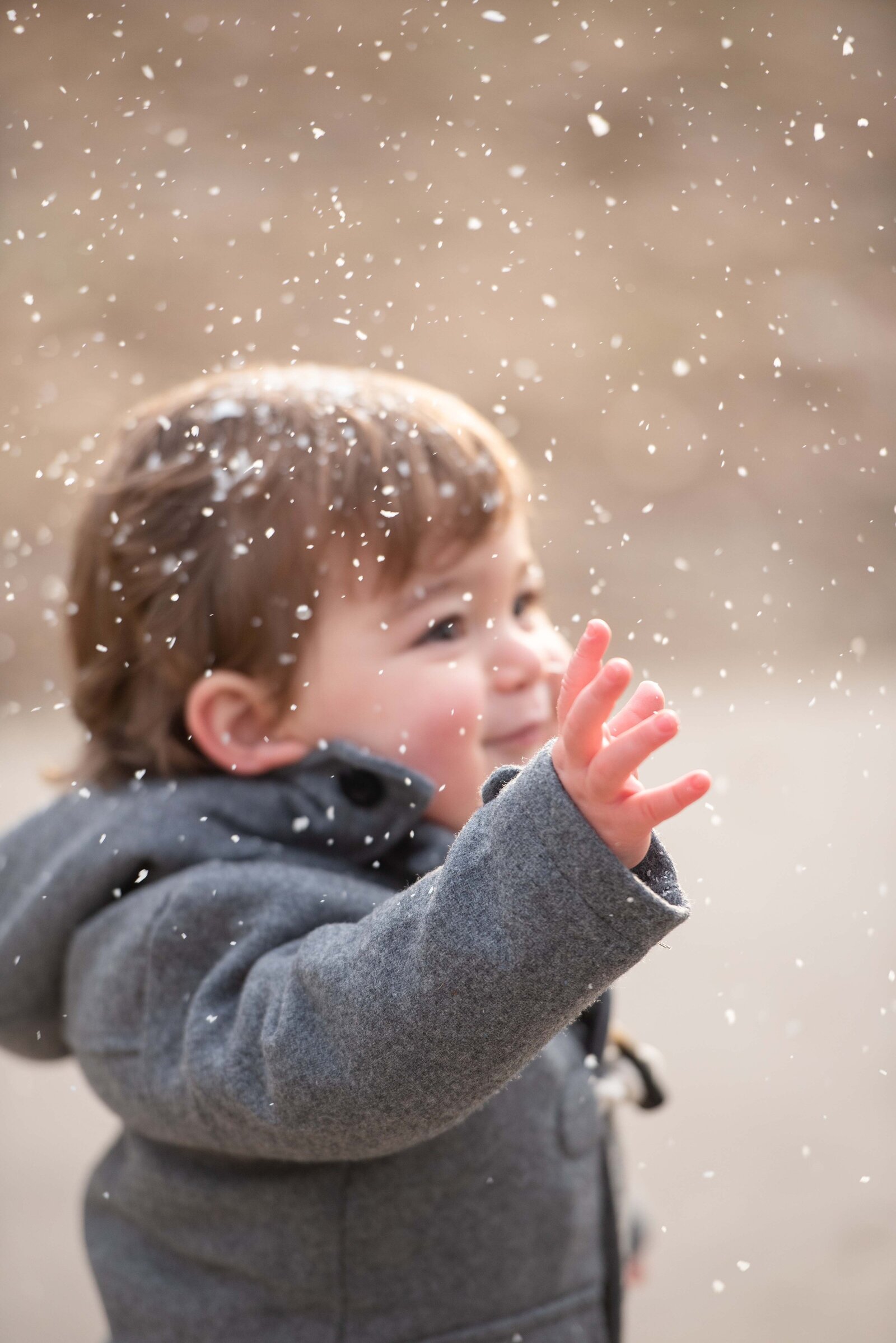 Toddler boy reaching out for snowflakes
