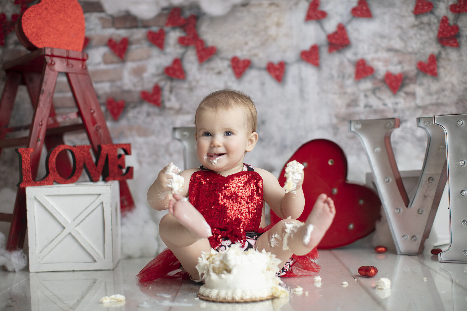 Valentine cake smash with little girl playing in cake.