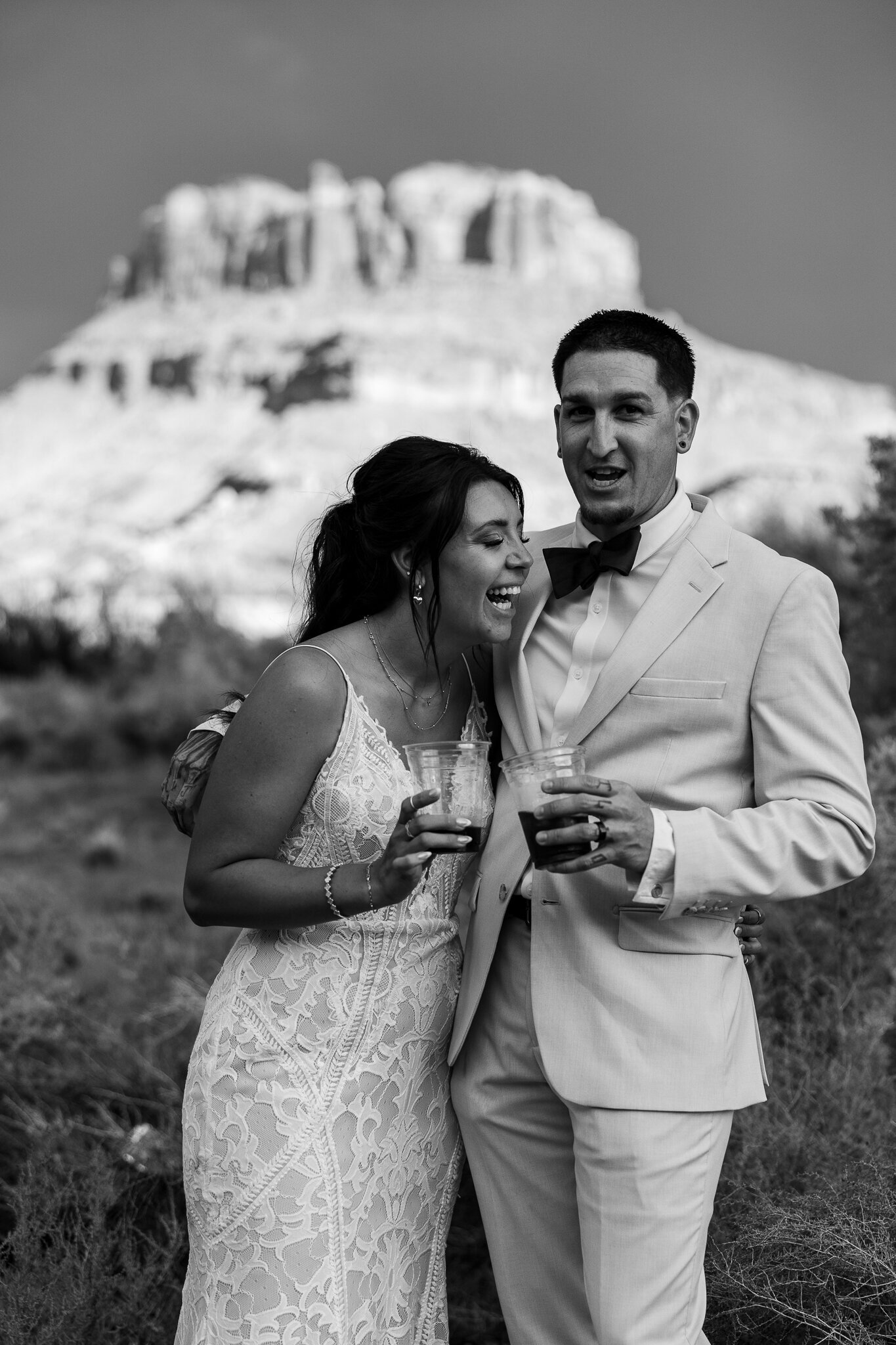 black and white image of bride and groom laughing during their photos with the mountain glowing in the background