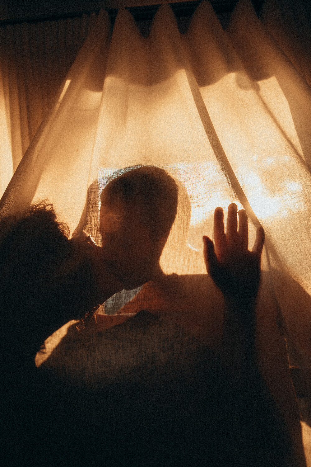 Couple silhouetted behind sunlit fabric during a storytelling photoshoot with a Sunshine Coast photographer
