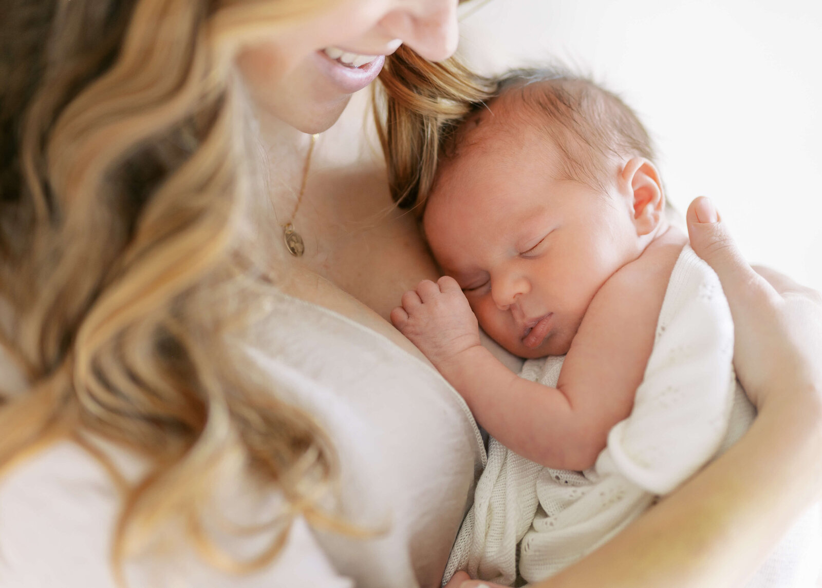 Mother cradling her newborn gently, with a serene expression and soft studio lighting.