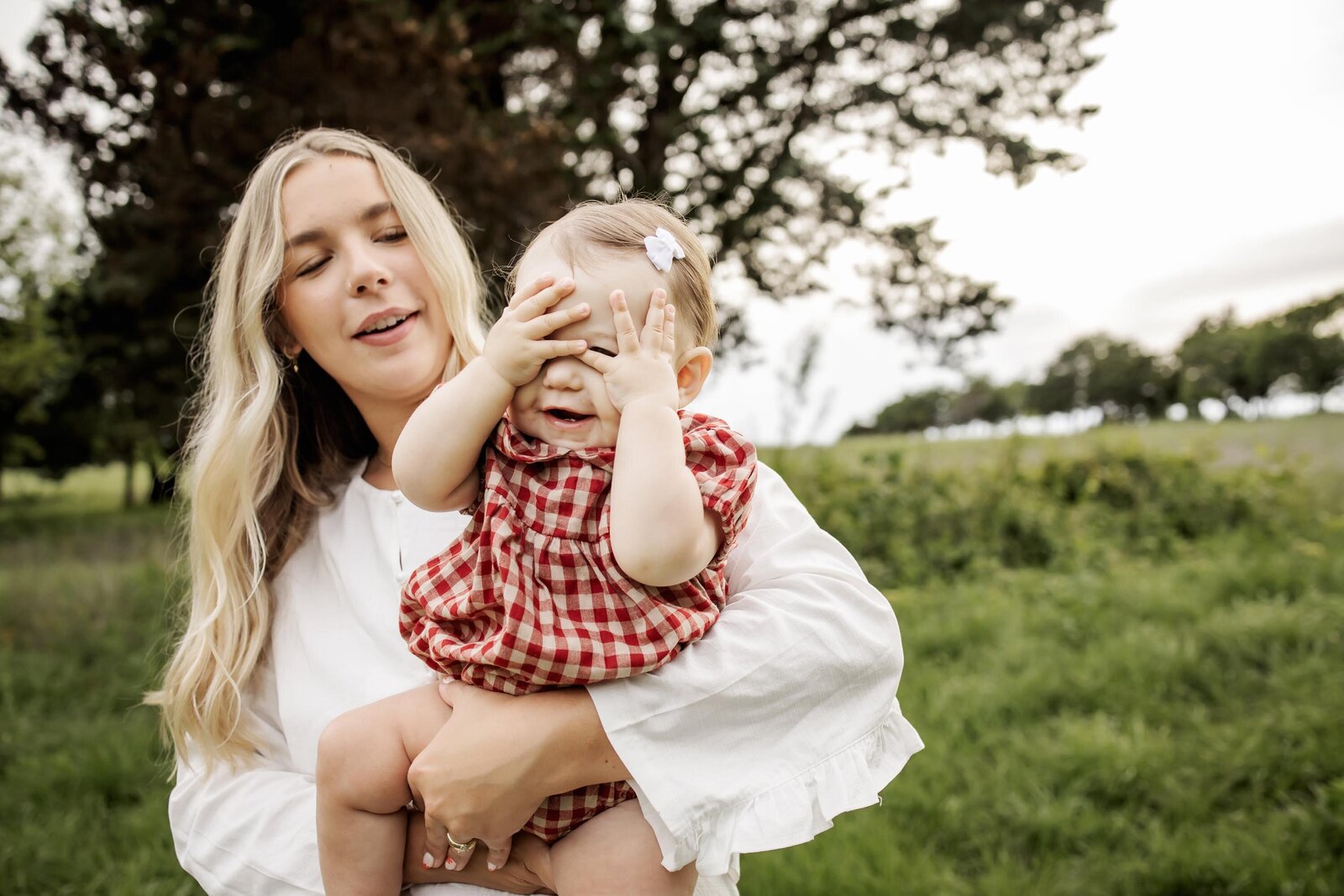 baby plays a game of peek a boo at a outdoors session in plano texas