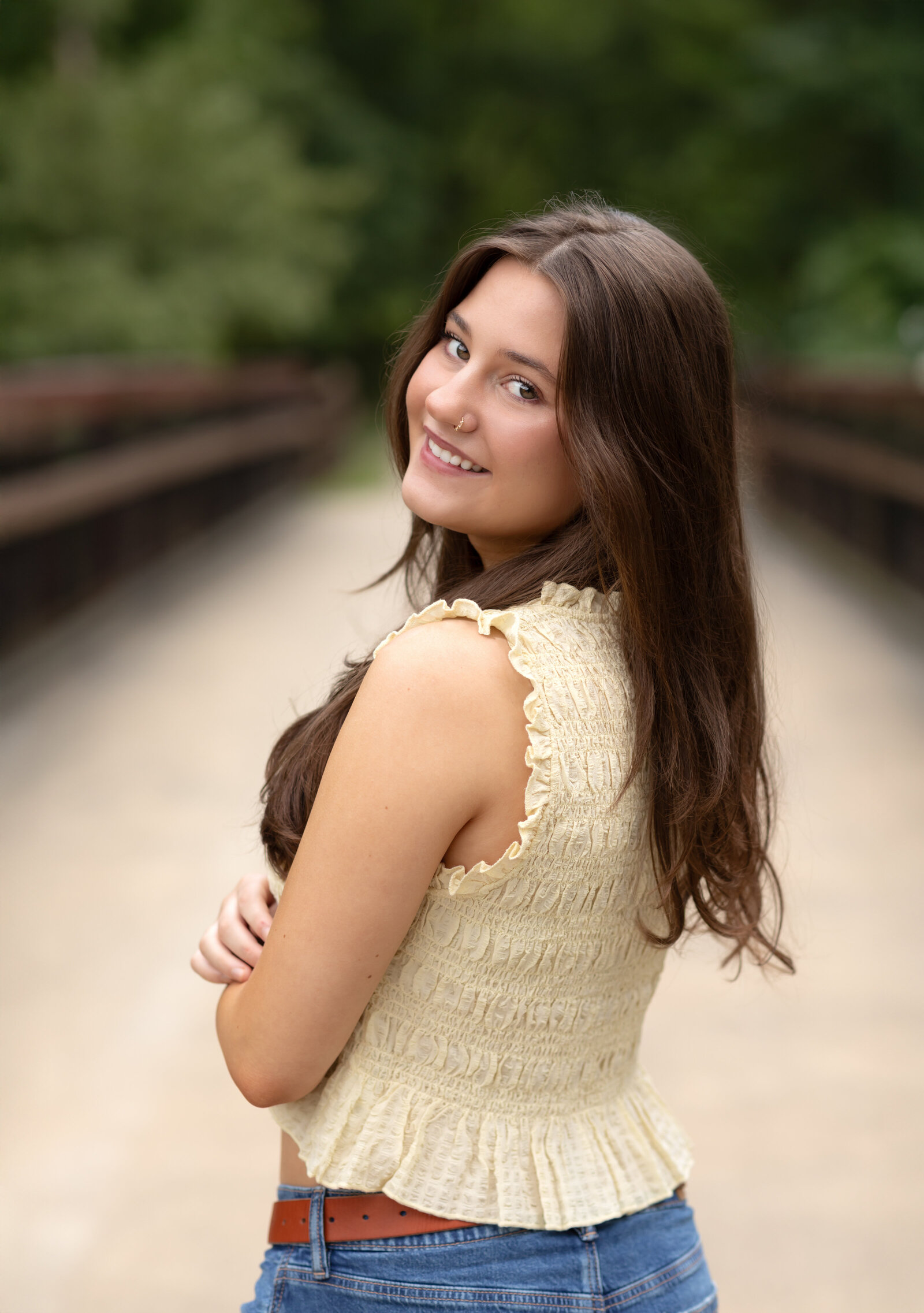 senior girl in yellow shirt looking over shoulder for senior photos