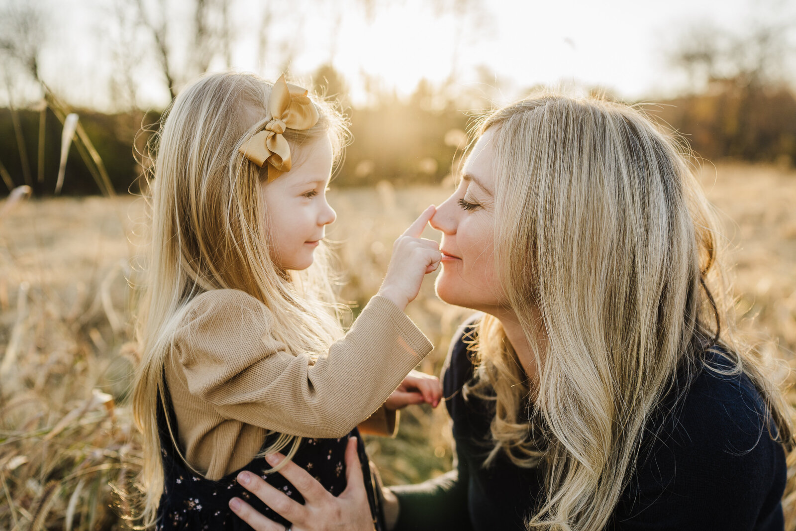 toddler girl touches nose of mom