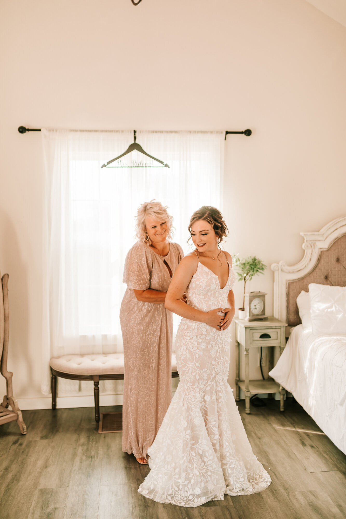 mother and daughter buttoning up the dress while laughing with each other
