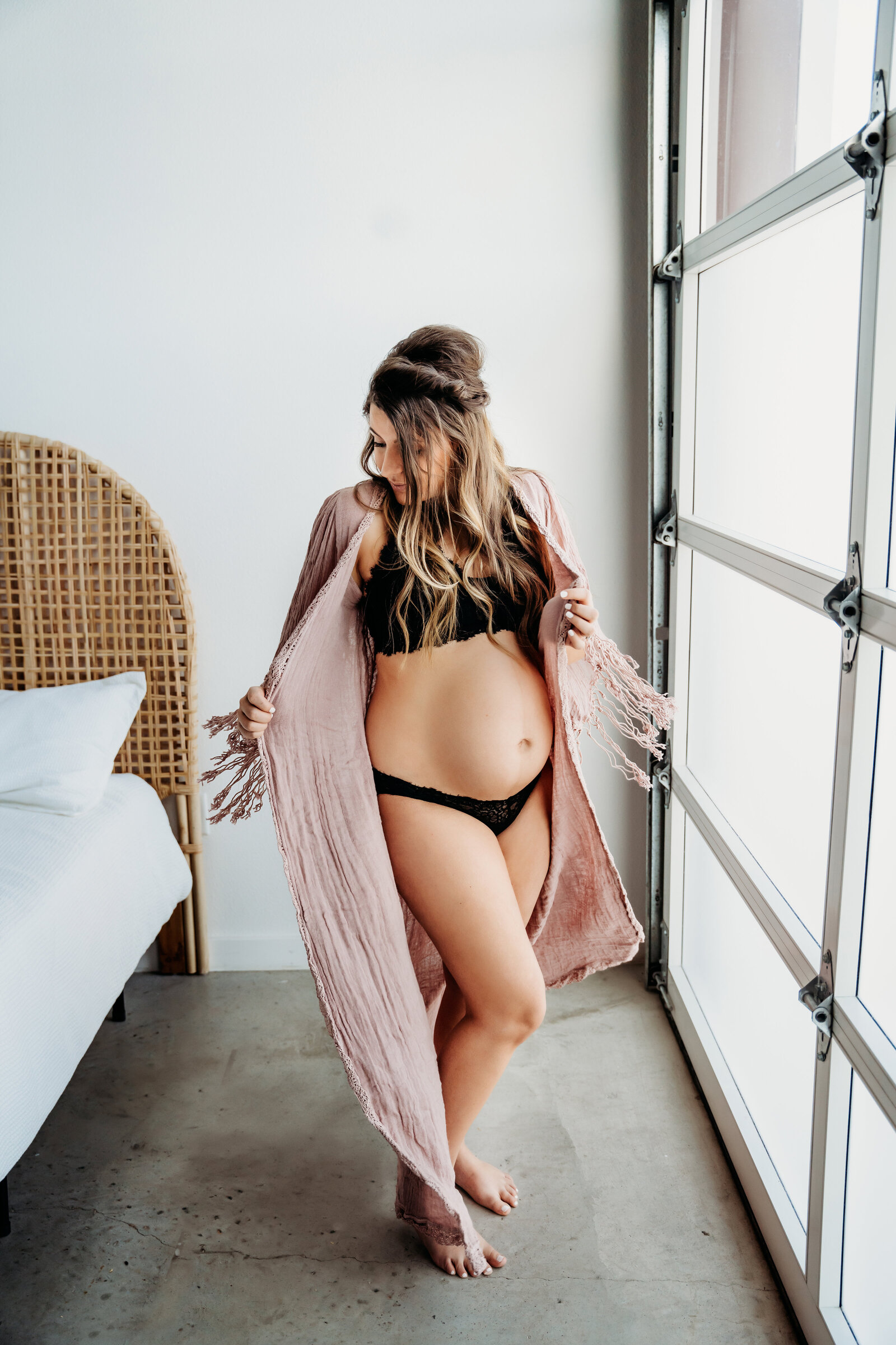 Maternity Photographer, an expectant mother dances as she holds onto her shawl, she wears a bikini beneath it showing a pregnant belly at home
