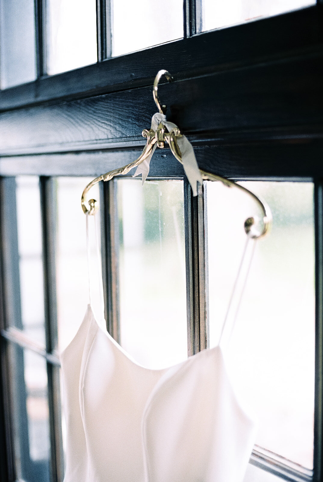 Wedding dress on antique gold hanger from anthropologie at Cottage at Riverbend Wedding by the Best Boise Wedding Photographers
