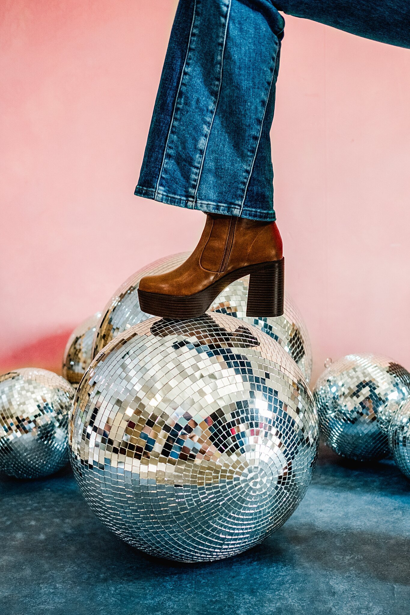 Studio photoshoot with disco balls all over the floor and a 70's retro boot stomping on one disco ball