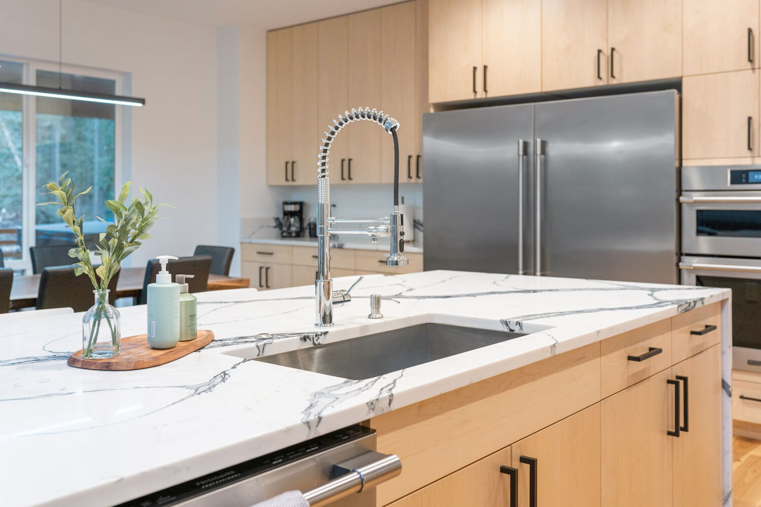 Kitchen island with marble countertop, stainless sink, and large refrigerator