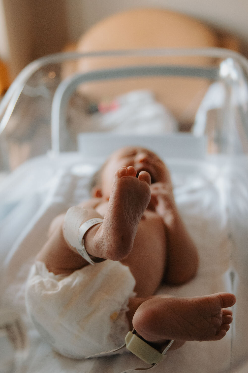 Close-up of a newborn baby stretching their legs in a hospital bassinet