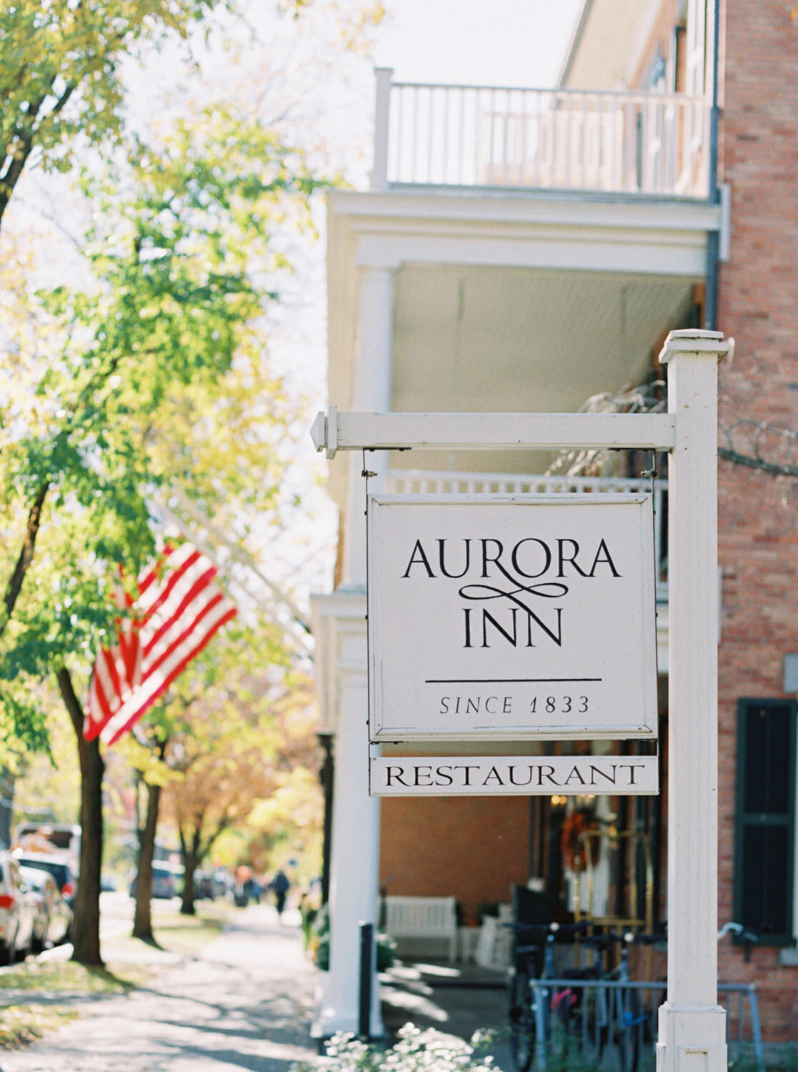 Sign of Aurora Inn with American flag in background.