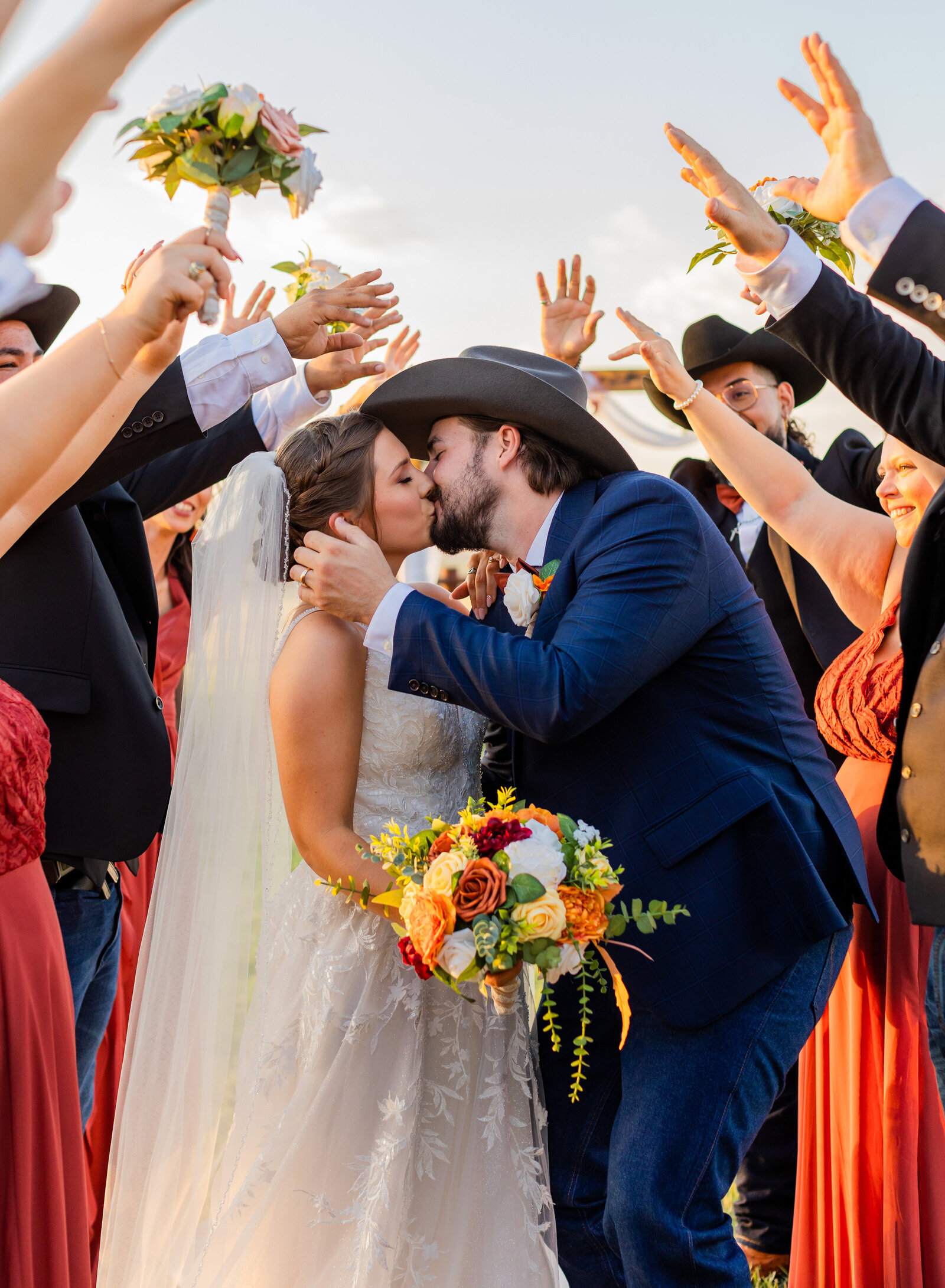 bride and groom kissing with wedding party cheering