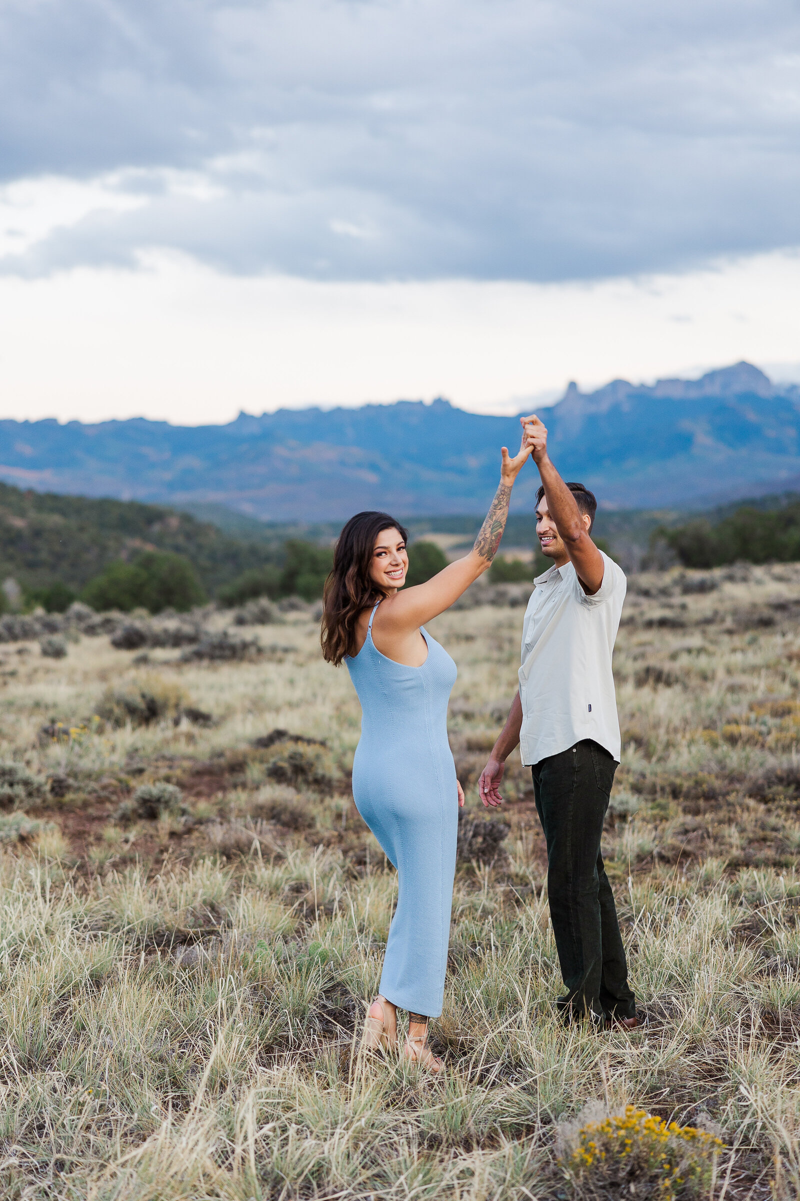 boy spins girlfriend in front of the rocky mountains