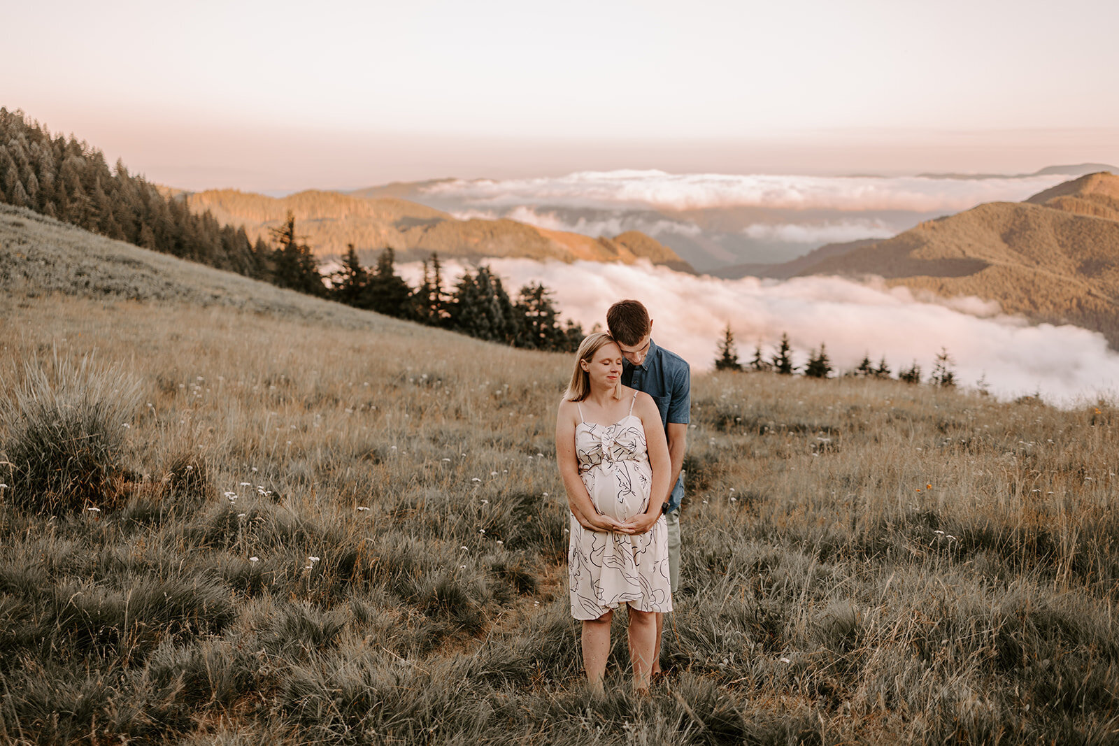 couple holding pregnant belly in the mountains
