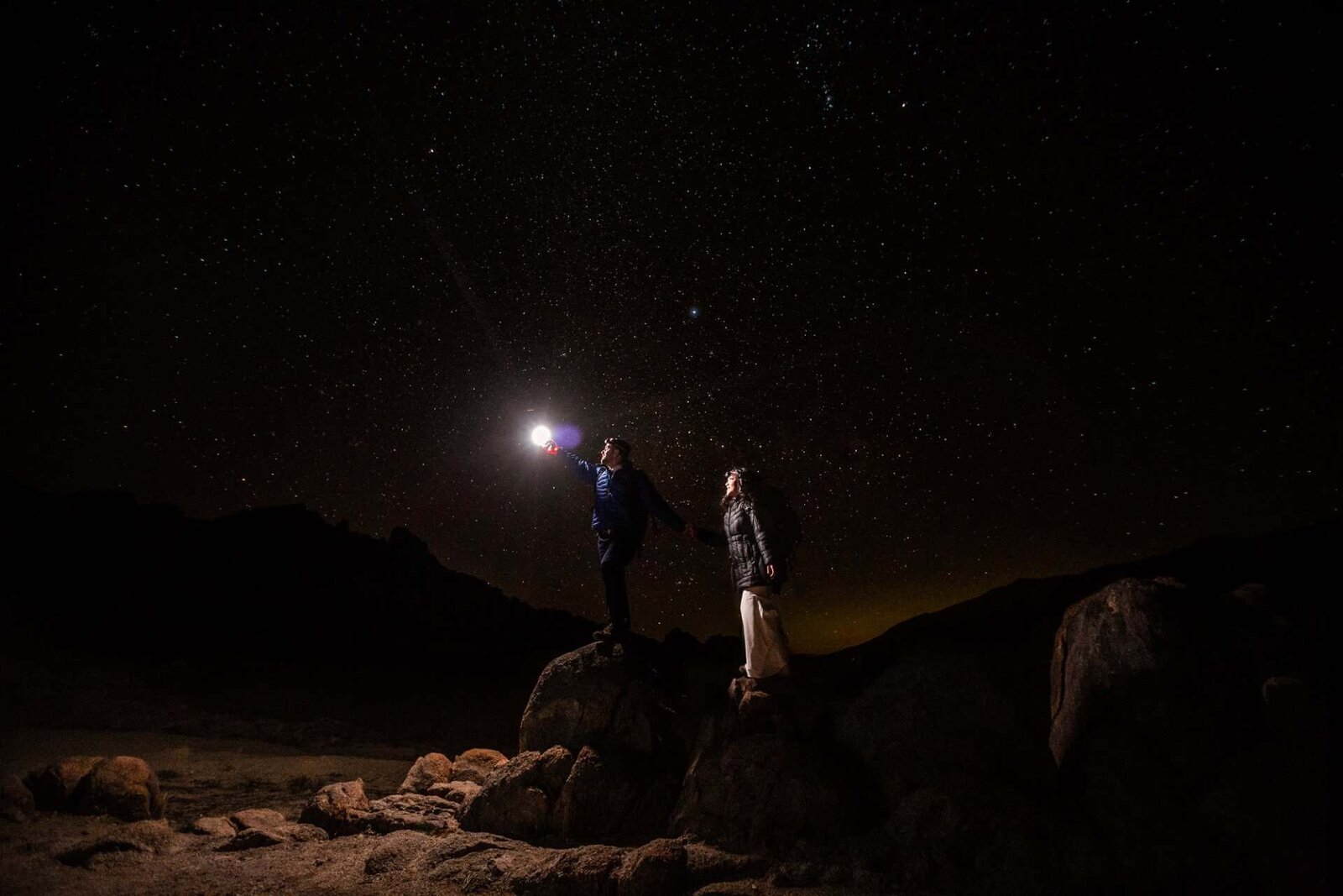 A bride and groom star gaze at night in the California desert.