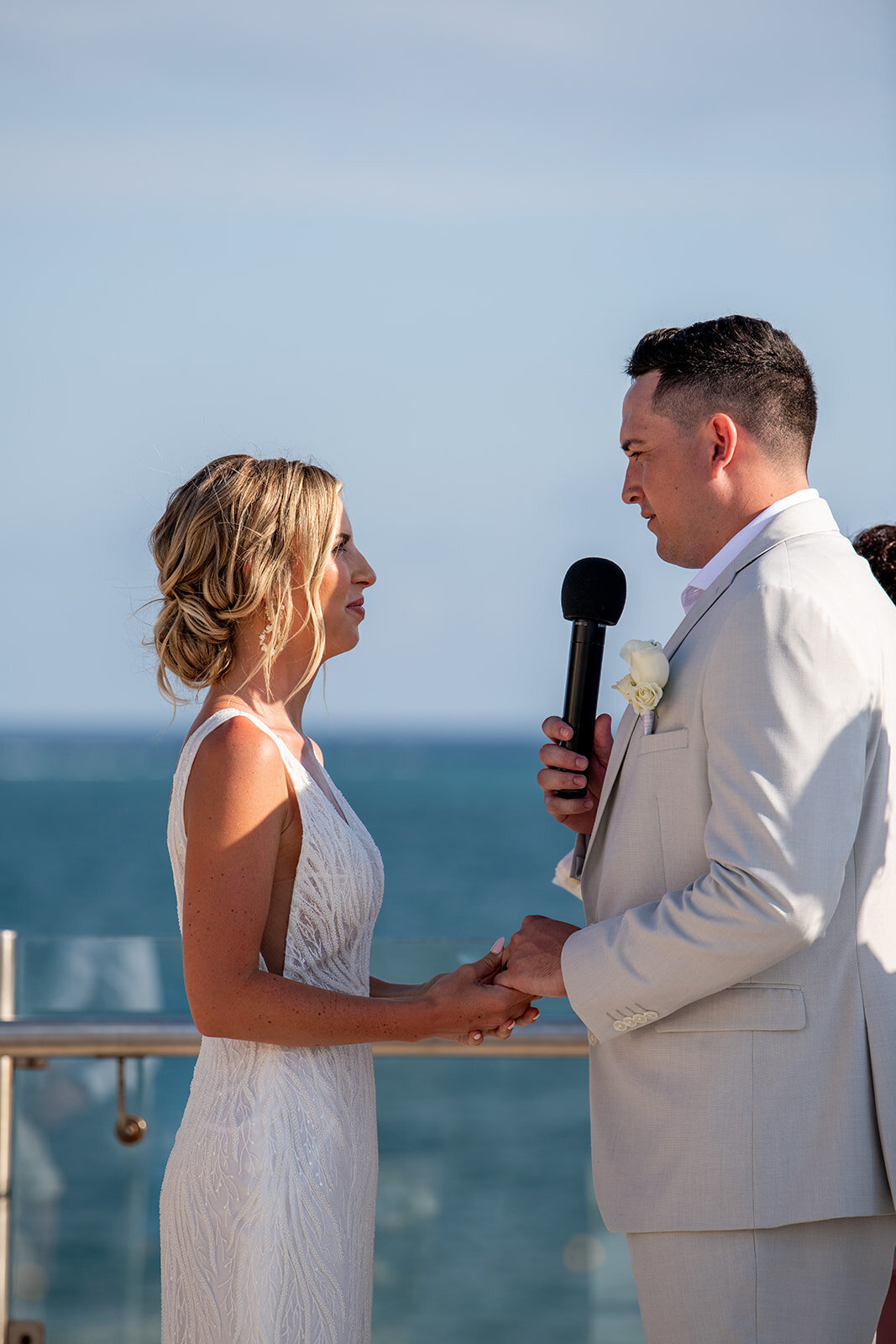A touching moment as the bride and groom exchange vows with the ocean as a backdrop, captured during a destination wedding by CMH Studios