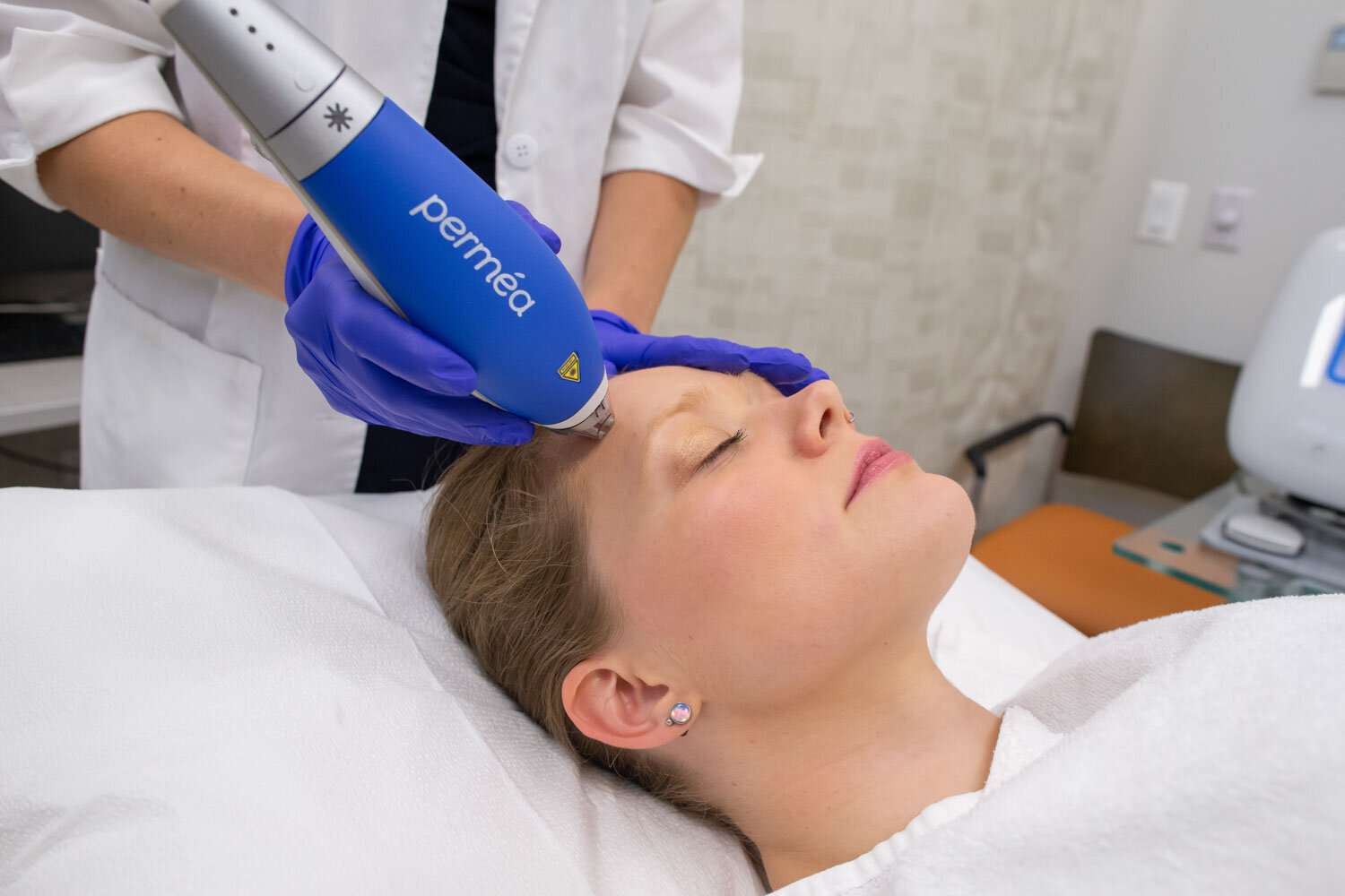 Woman receives a laser facial treatment with a Permea device