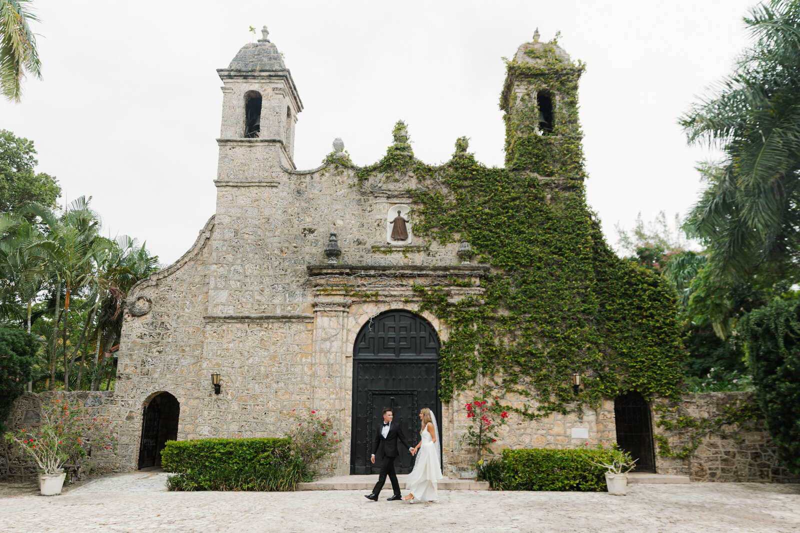 Bride and Groom walk along the from entrance of Plymouth Congregational Church in Coconut Groves, Florida. Photo by Maggie Alvarez Photography