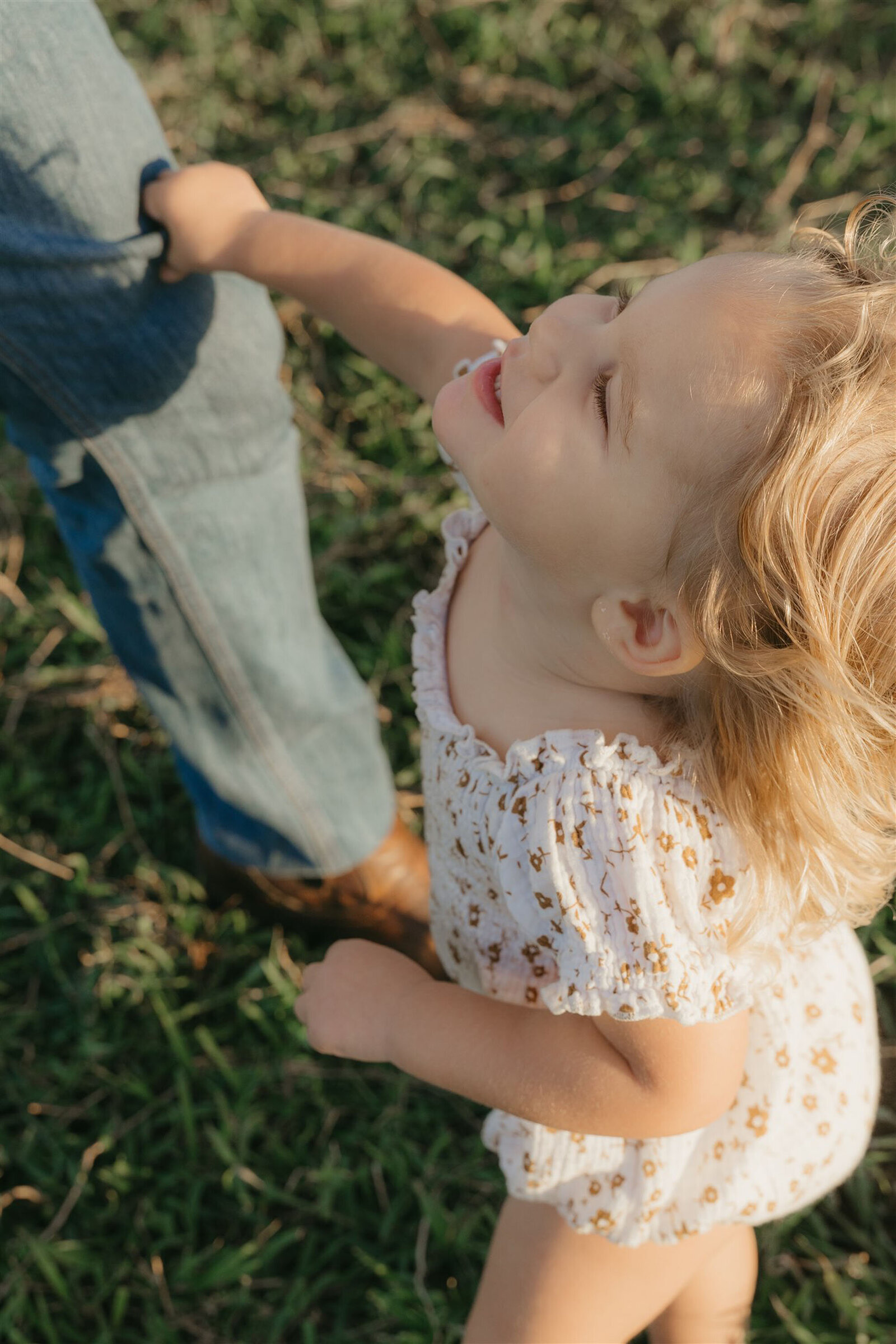 Styled Maui family photography session on a cliffside, capturing candid laughter and connection in denim and neutral tones.