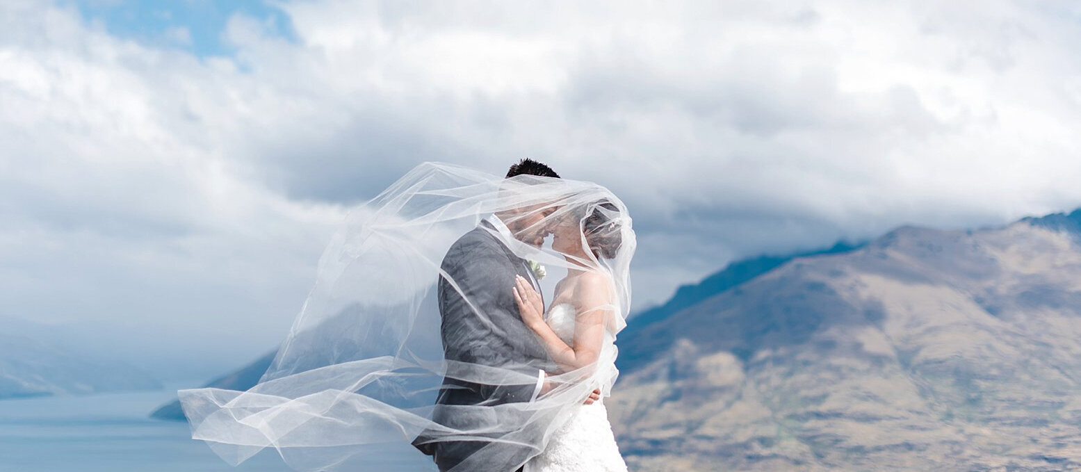 bride groom on top of a mountain queenstown helicopter wedding elopement new zealand veil wind