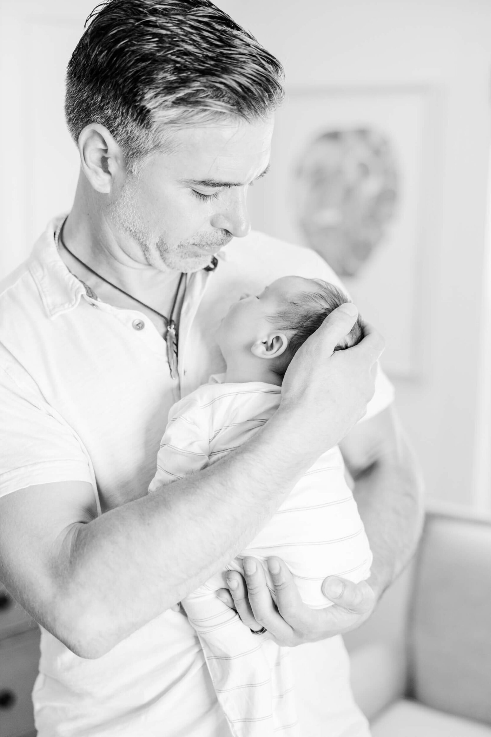 Dad looking down at the newborn he is cradling, black and white