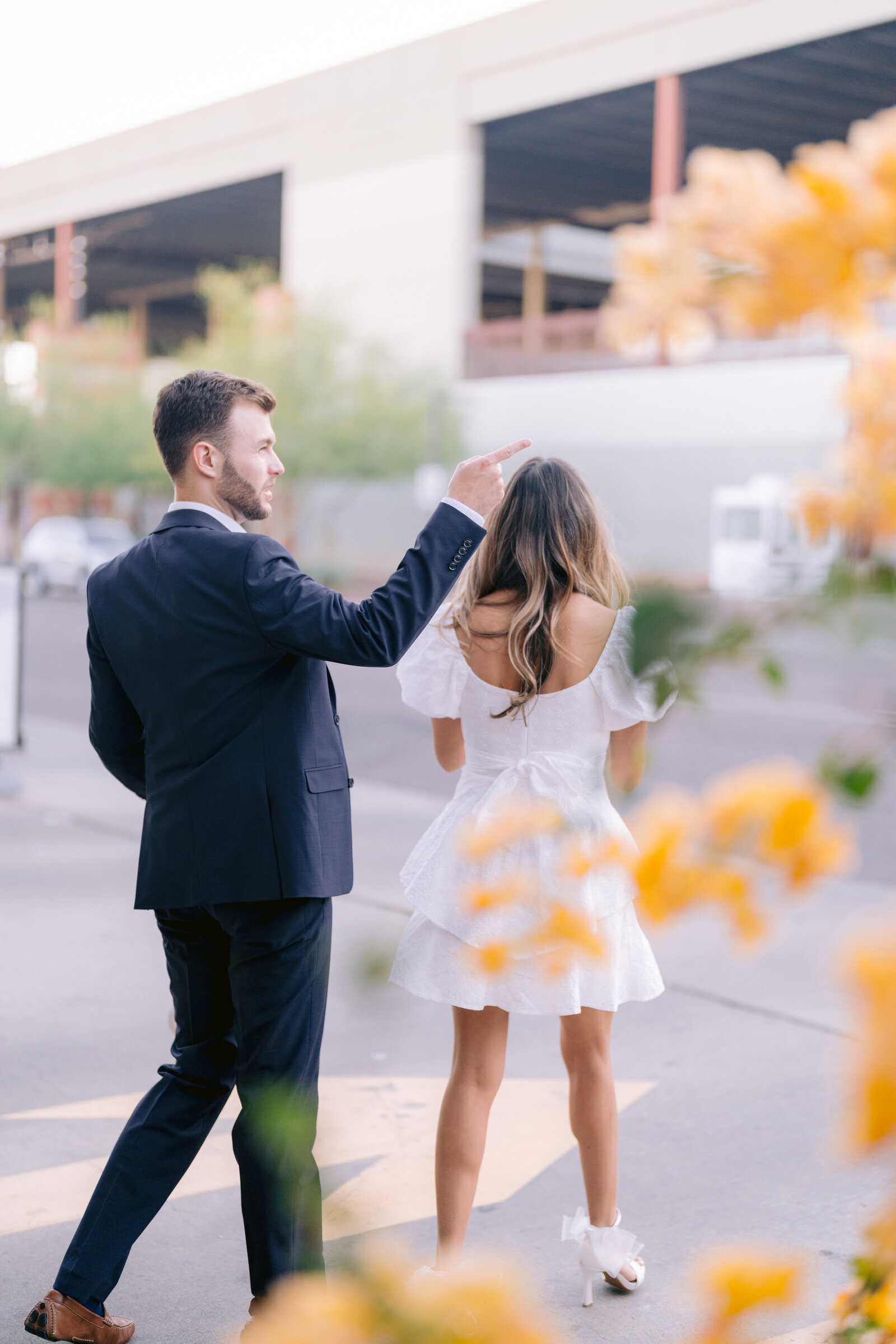 Artsy engagement photo of dressed up couple crossing the street in downtown Phoenix Arizona