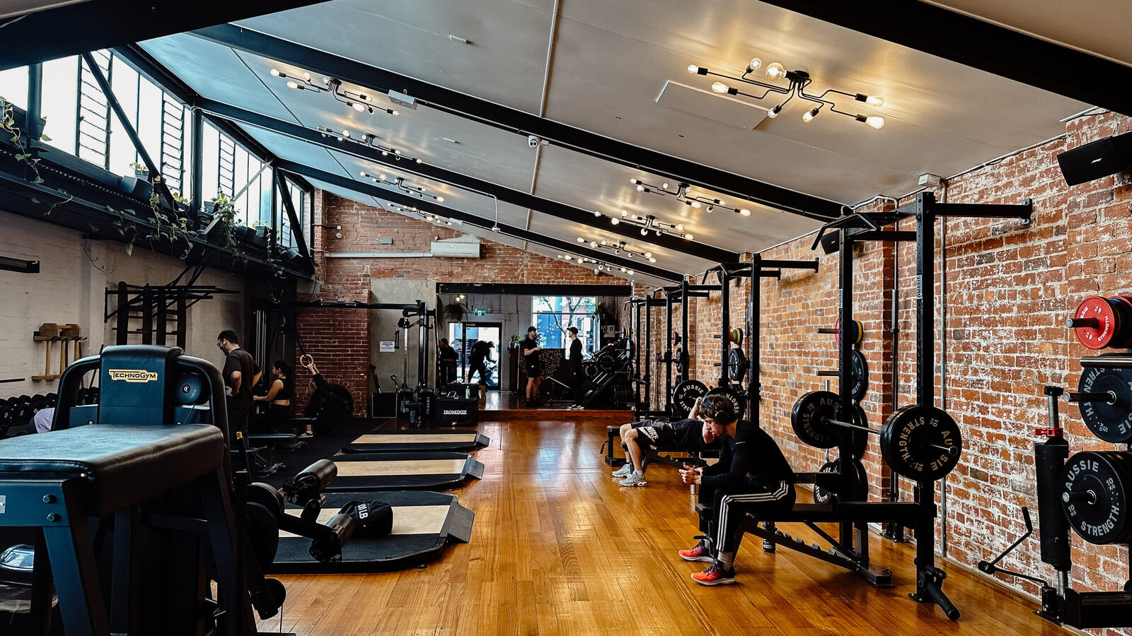 Bright gym interior with weightlifting platforms and brick walls in a Collingwood gym.