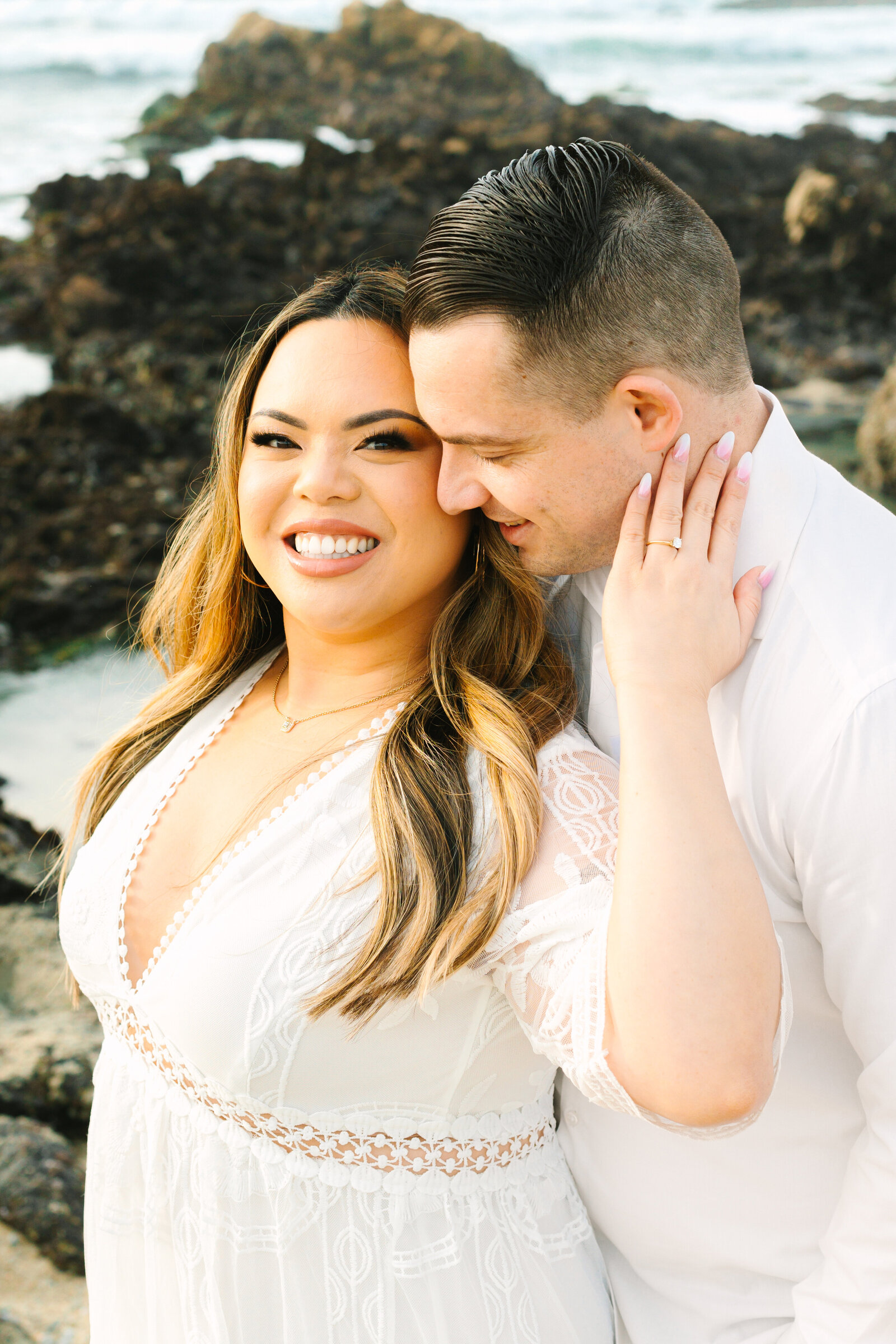 An engaged man and woman take photos on the beach in Pacific Grove, Monterey, California near Big Sur.