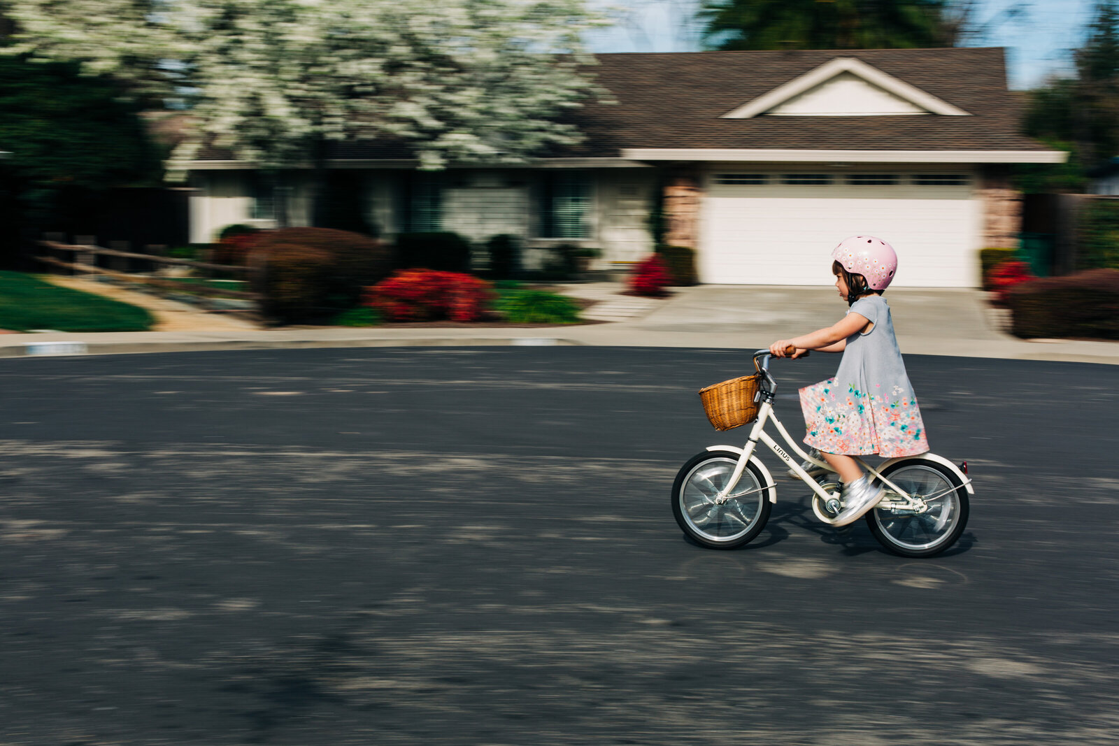 panning image of young girl on bicycle with a basket on the front
