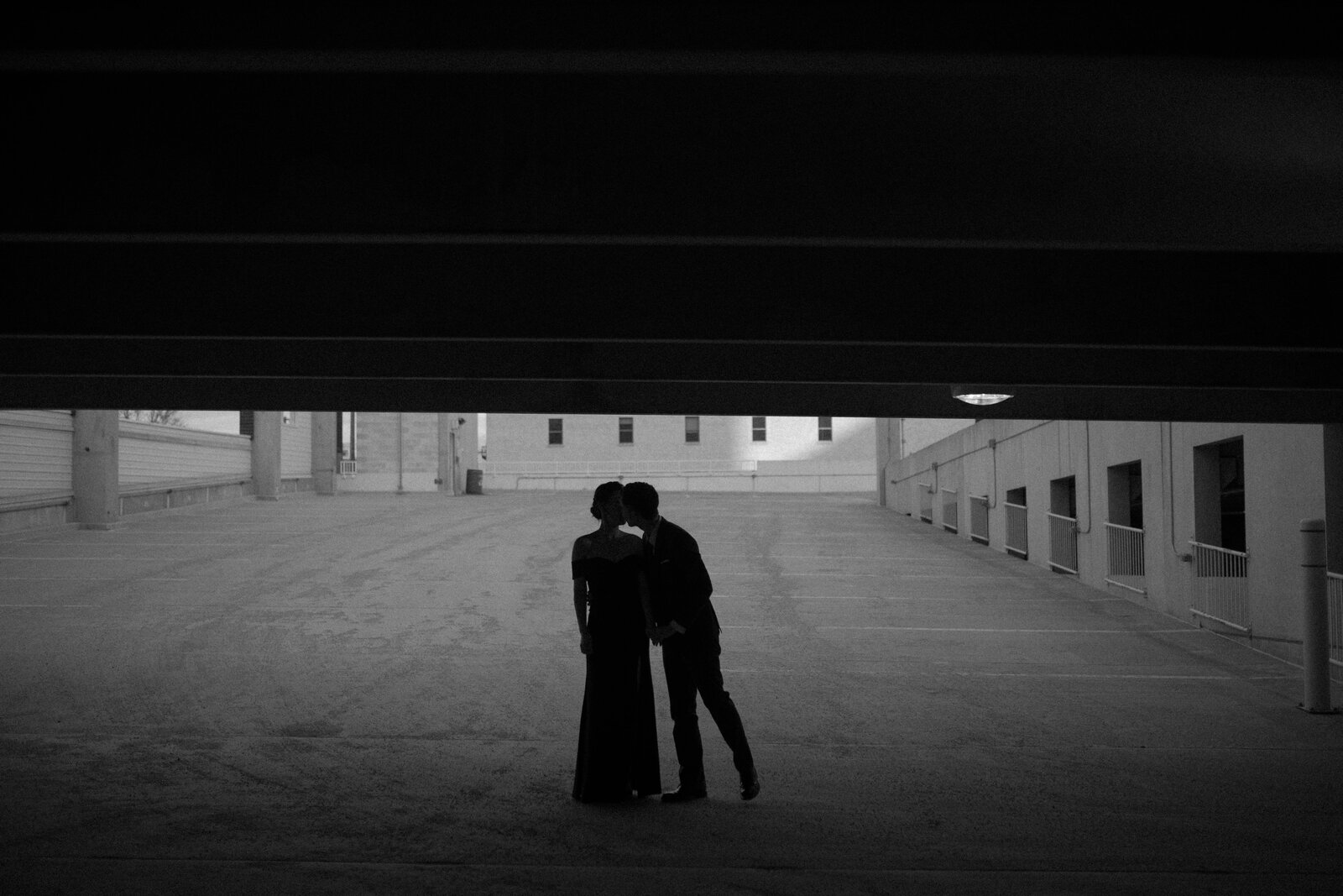 black and white image of couple embracing in a parkade