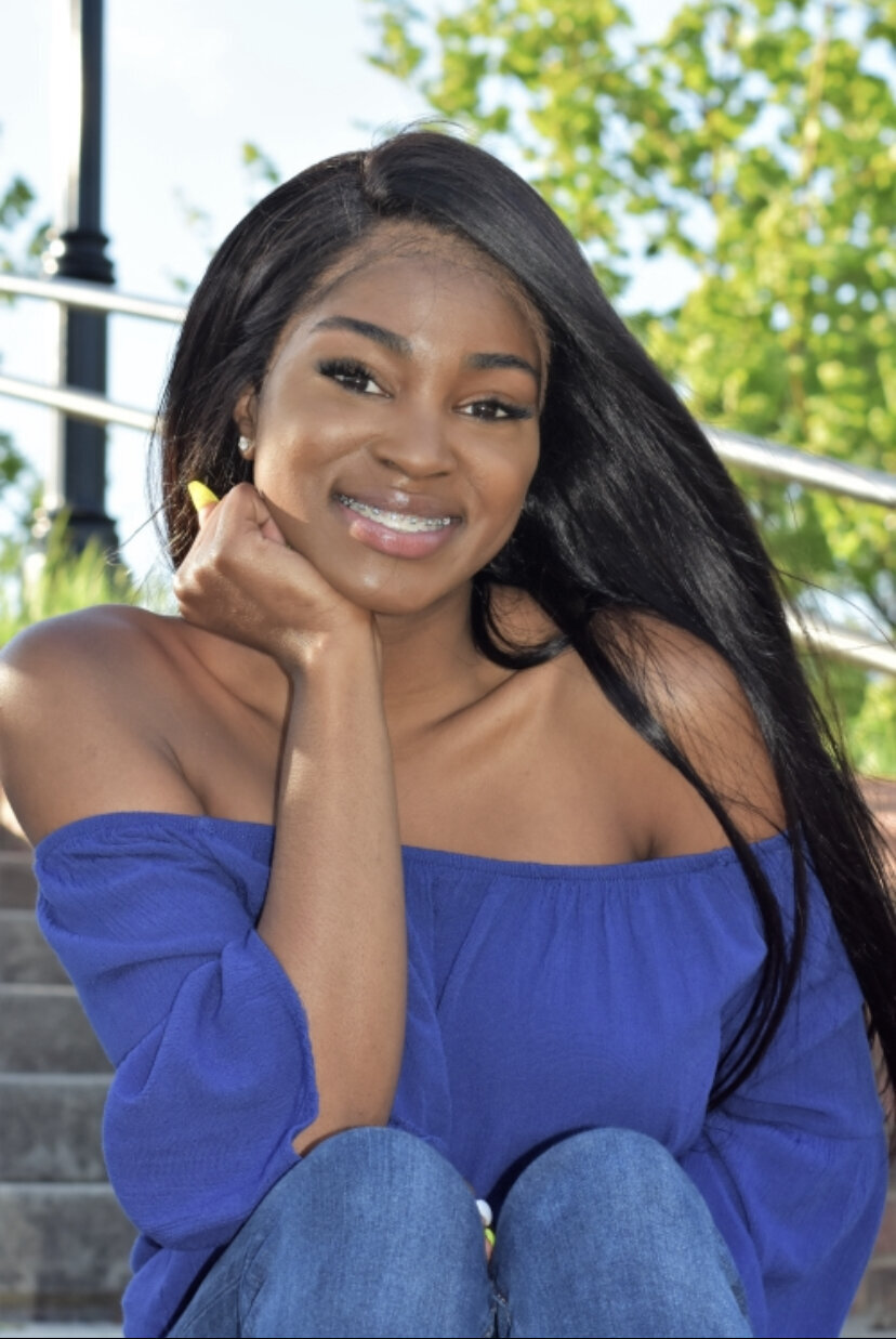 a high school senior sitting on stairs posing for her graduation photo photographed by Millz Photography in Greenville, SC