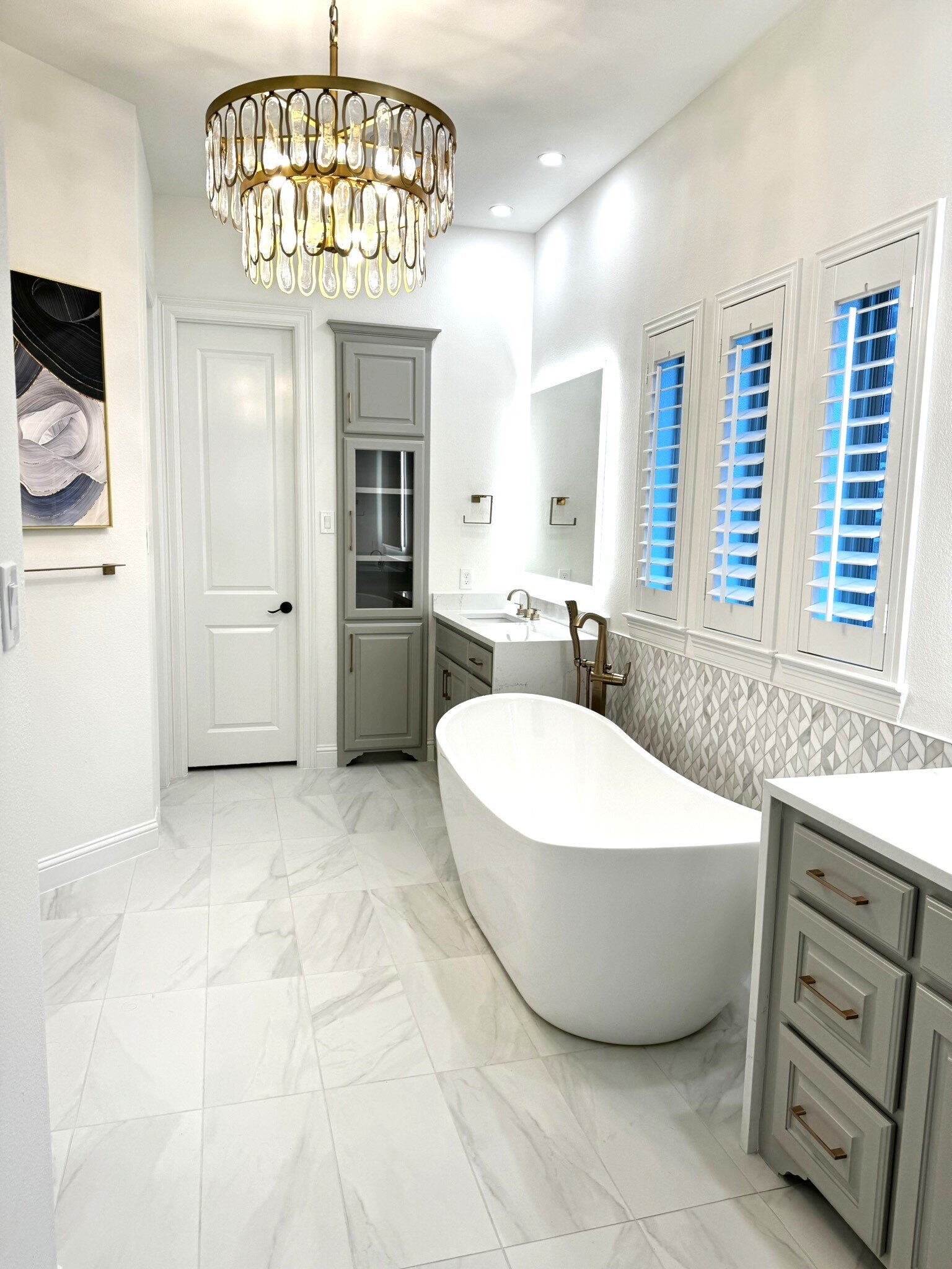 Modern interior design in Frisco for a small but elegant bathroom, featuring a beautiful white tub and a large crystal ceiling lamp.