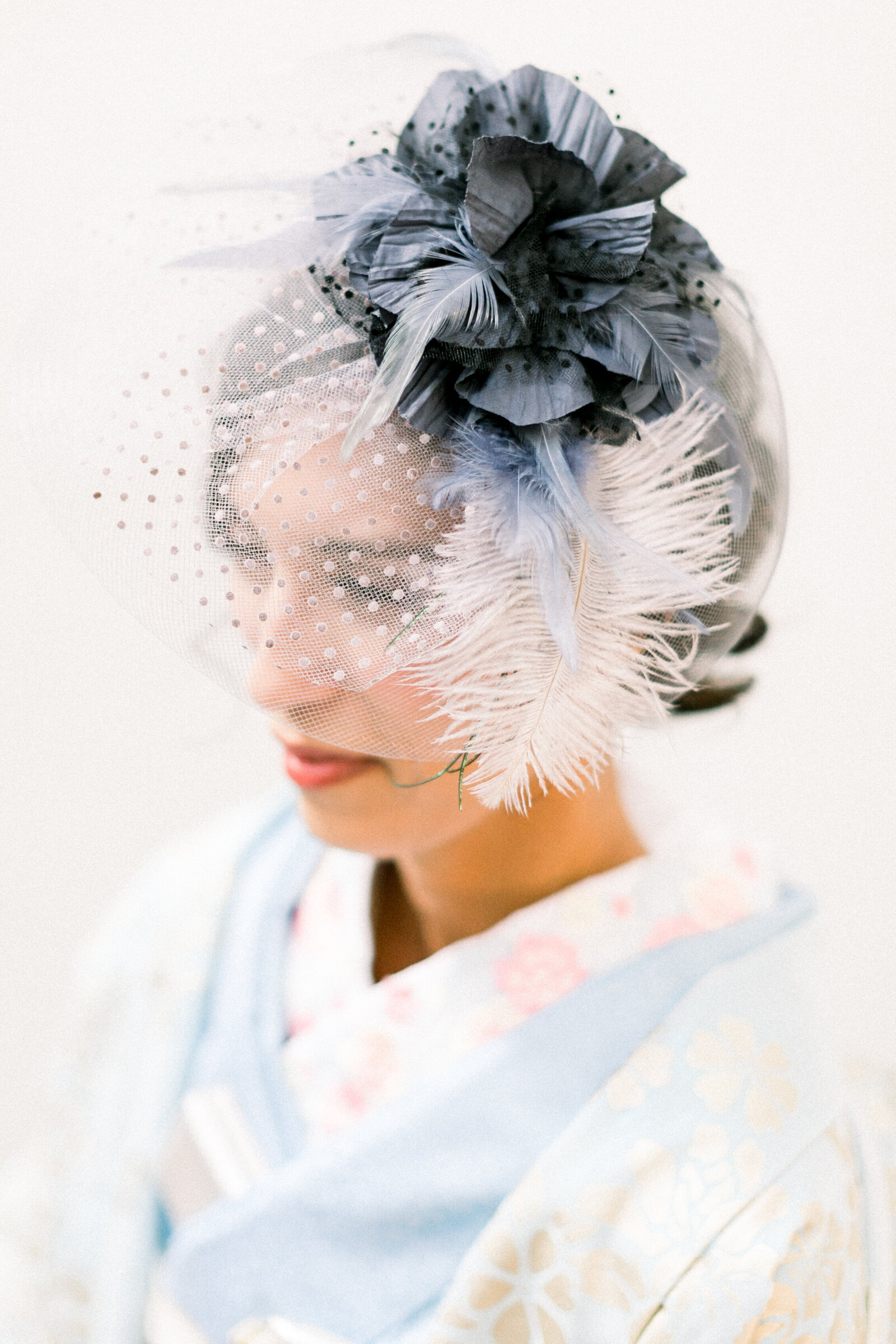 Elegant bride wearing a soft blue wedding kimono with delicate gold patterns and a dramatic feathered hat at The Ebell Club Long Beach, perfect for kimono rental in Los Angeles | ロサンゼルスのThe Ebell Club Long Beachで羽根付きハットを合わせた淡いブルーと金模様の花嫁着物レンタル