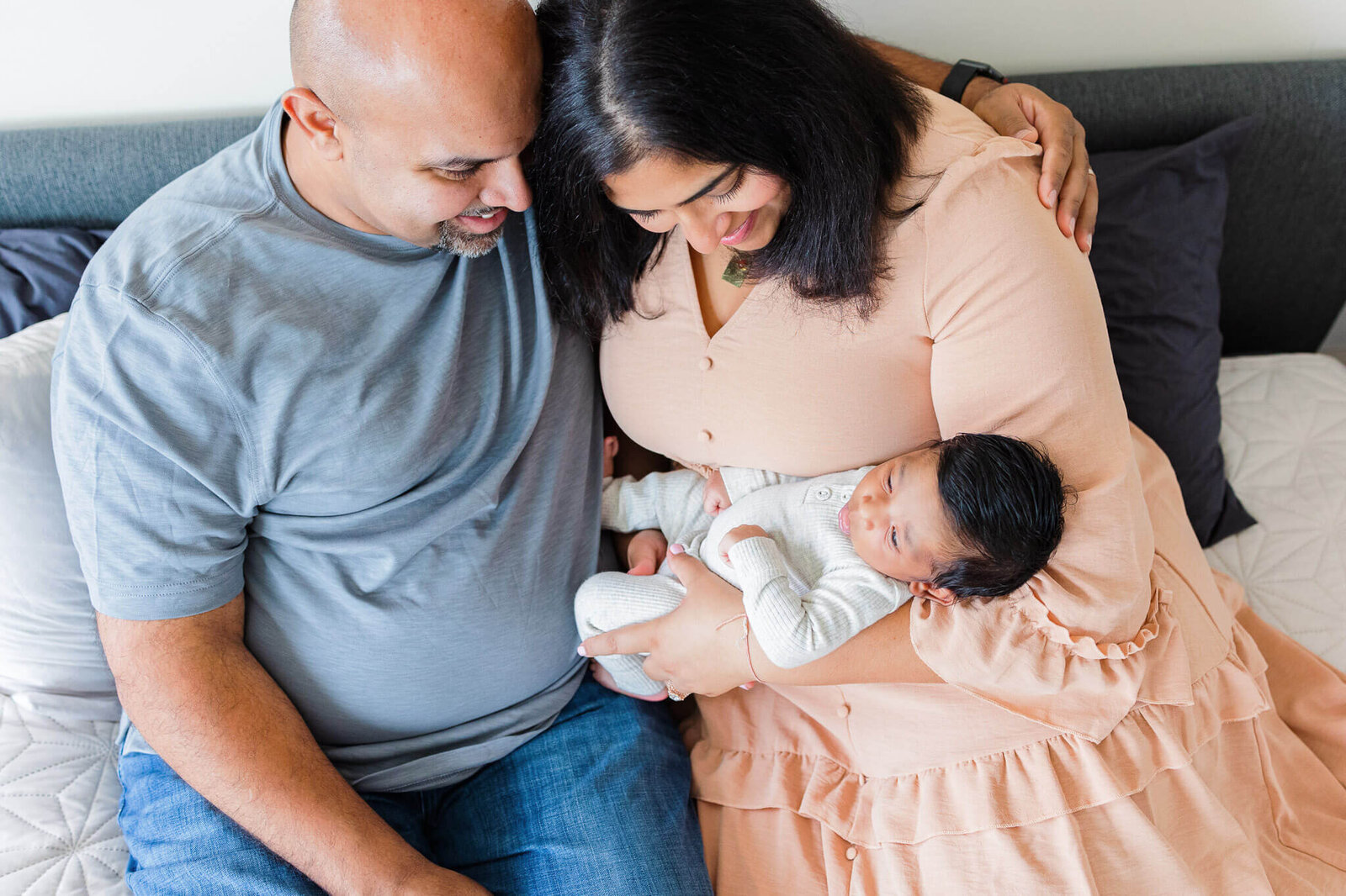 A couple snuggling their newborn son.